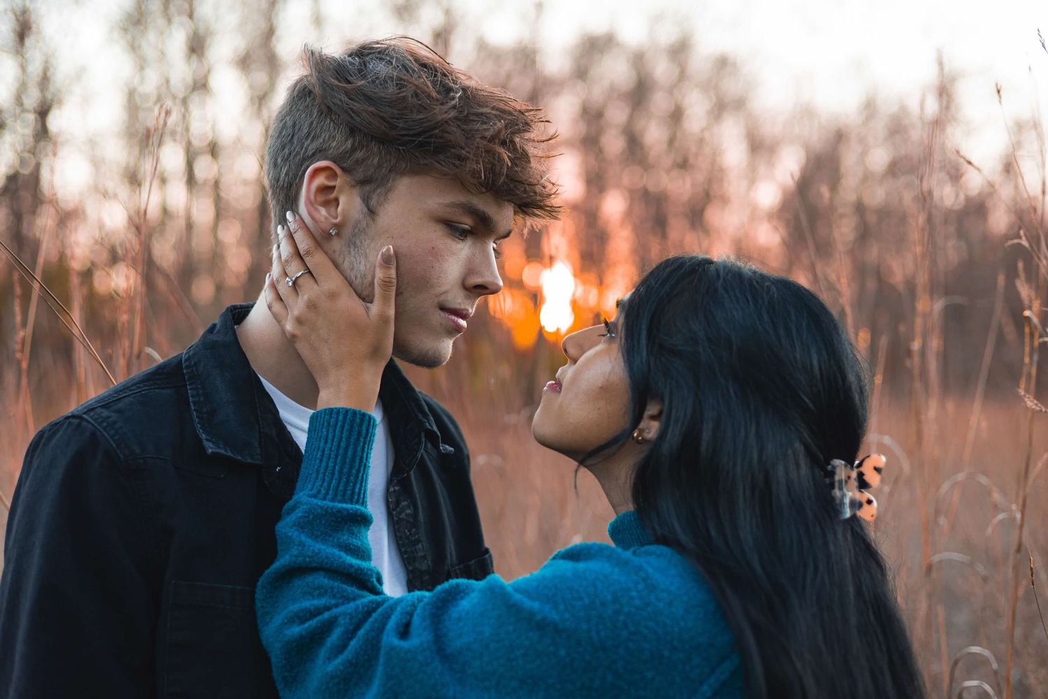 Romantic couple sharing intimate moment at sunset in field of tall grass.