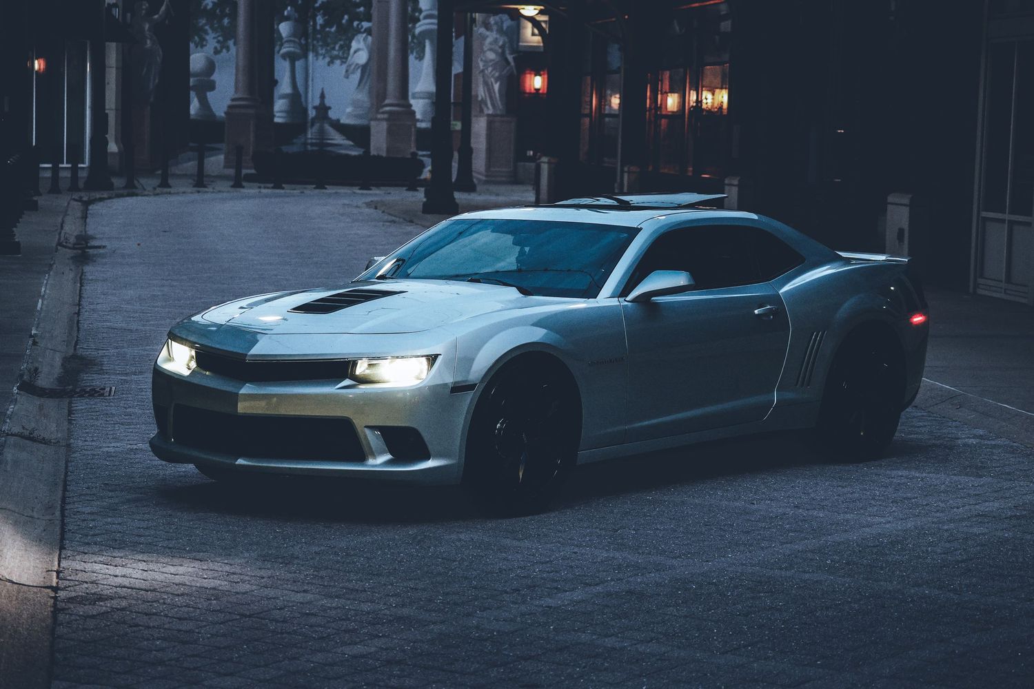 Modern sports cars lined up in a dimly lit parking area during evening hours.
