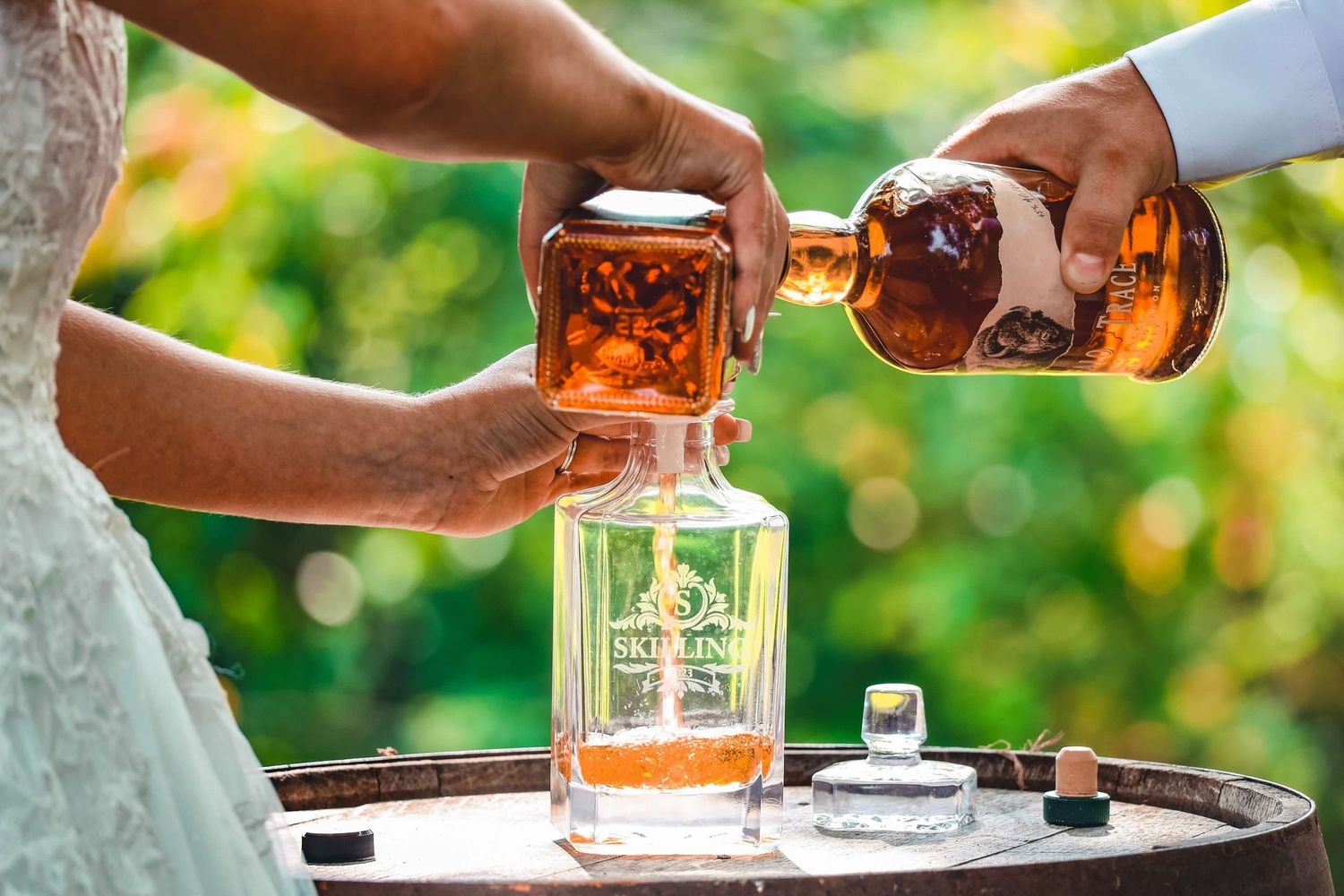 Wedding party pouring and sharing drinks outdoors with natural greenery background.
