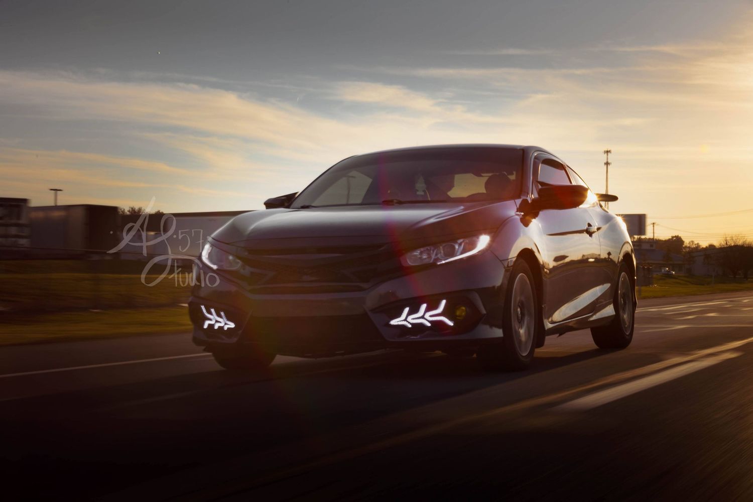 Silhouettes of cars against a dramatic sunset sky.