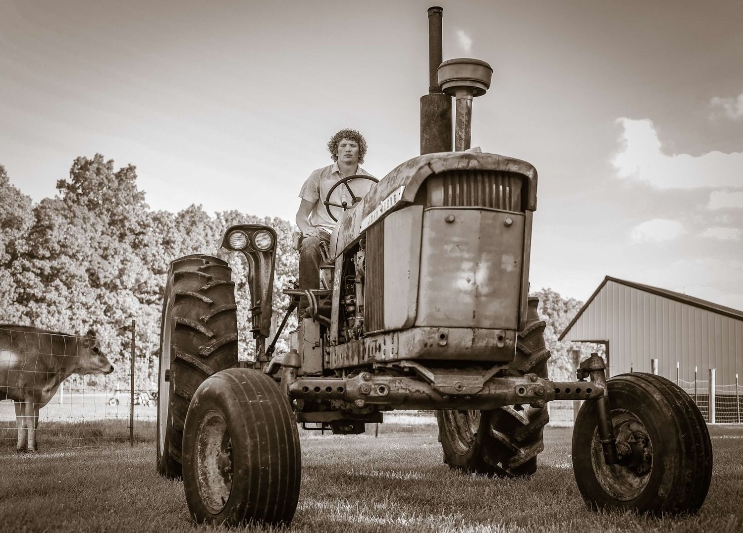 Vintage sepia photograph of old farm tractors in rural setting.