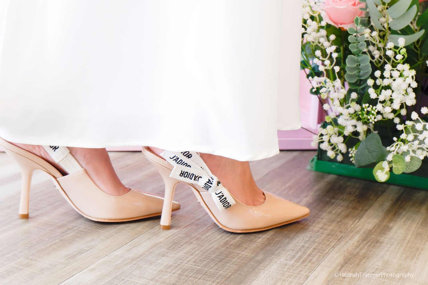 Close-up of bride to be wearing designer nude stiletto heels with branded ribbon at a bridal event.