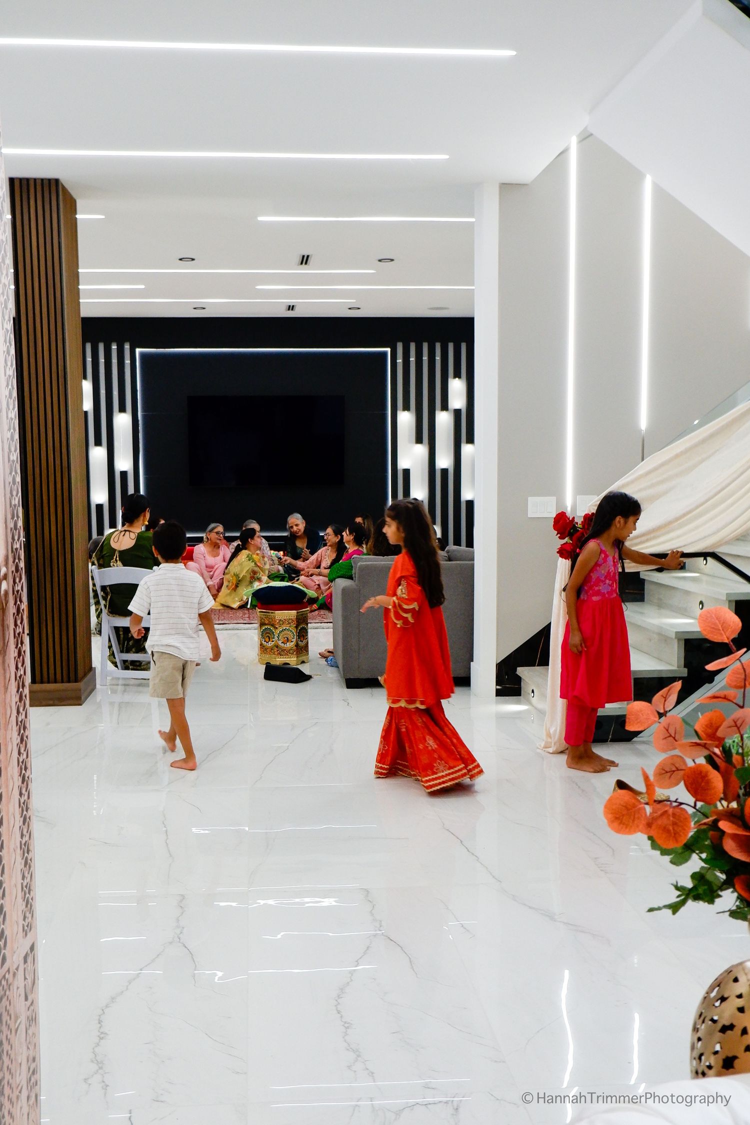 Children playing in a modern home foyer during a traditional Indian wedding pre-ceremony celebration.