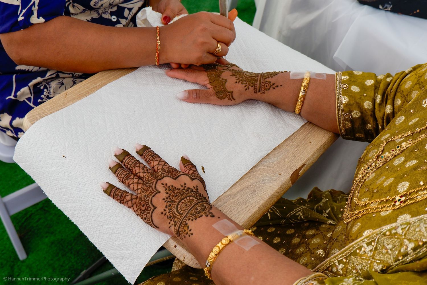 Detailed traditional henna mehndi design on hands resting on paper towel at Indian wedding ceremony.