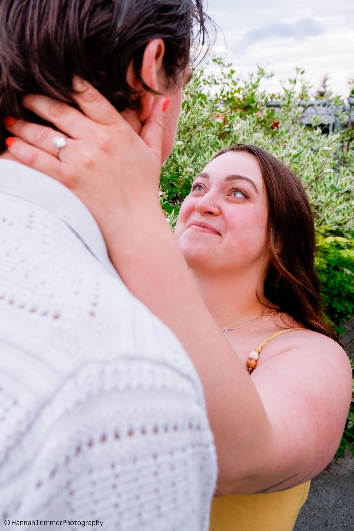 Woman gazing lovingly at her partner while gently holding his face in a garden.