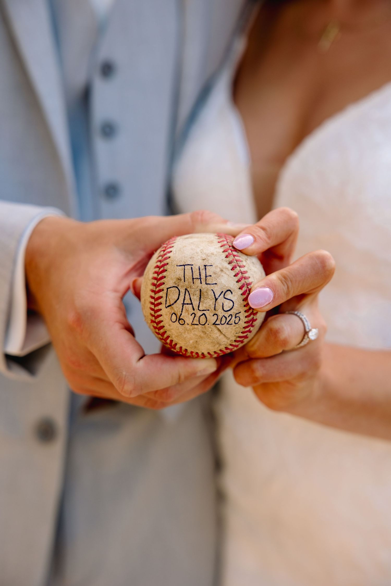 Bride and groom holding a personalized wedding baseball inscribed with The Dalys and date 06.20.2025.