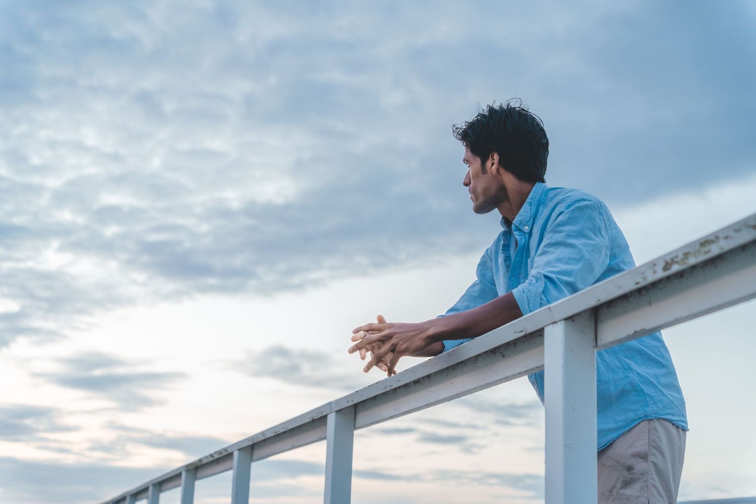Creative Photography of a young Indian man leaning against a wooden railing. Captured by Photopazo, a photographer in Malmö, Sweden.