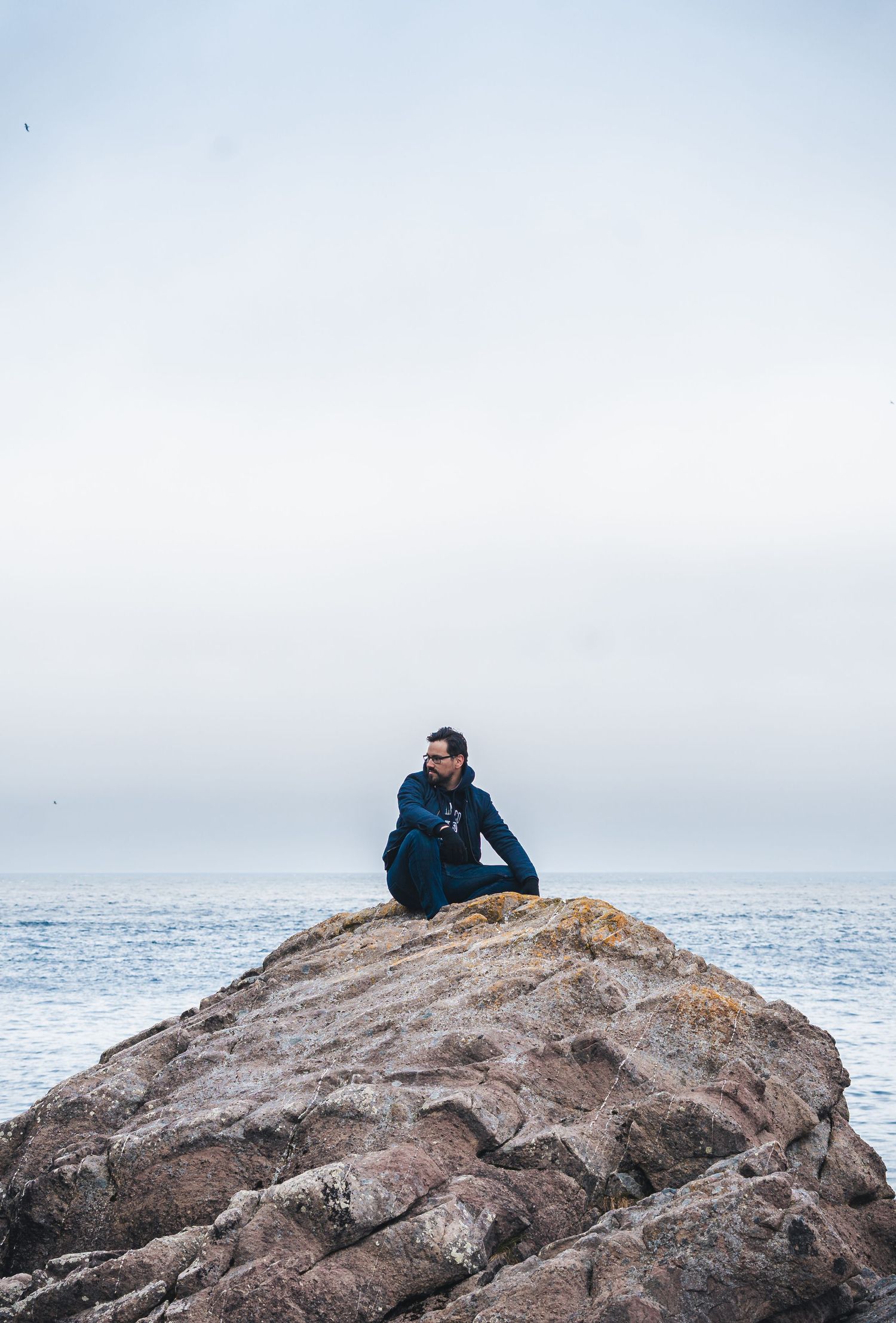 Self-portrait of Cristian as he sits on a rock by the sea. Captured by Photopazo, a photographer in Malmö, Sweden.