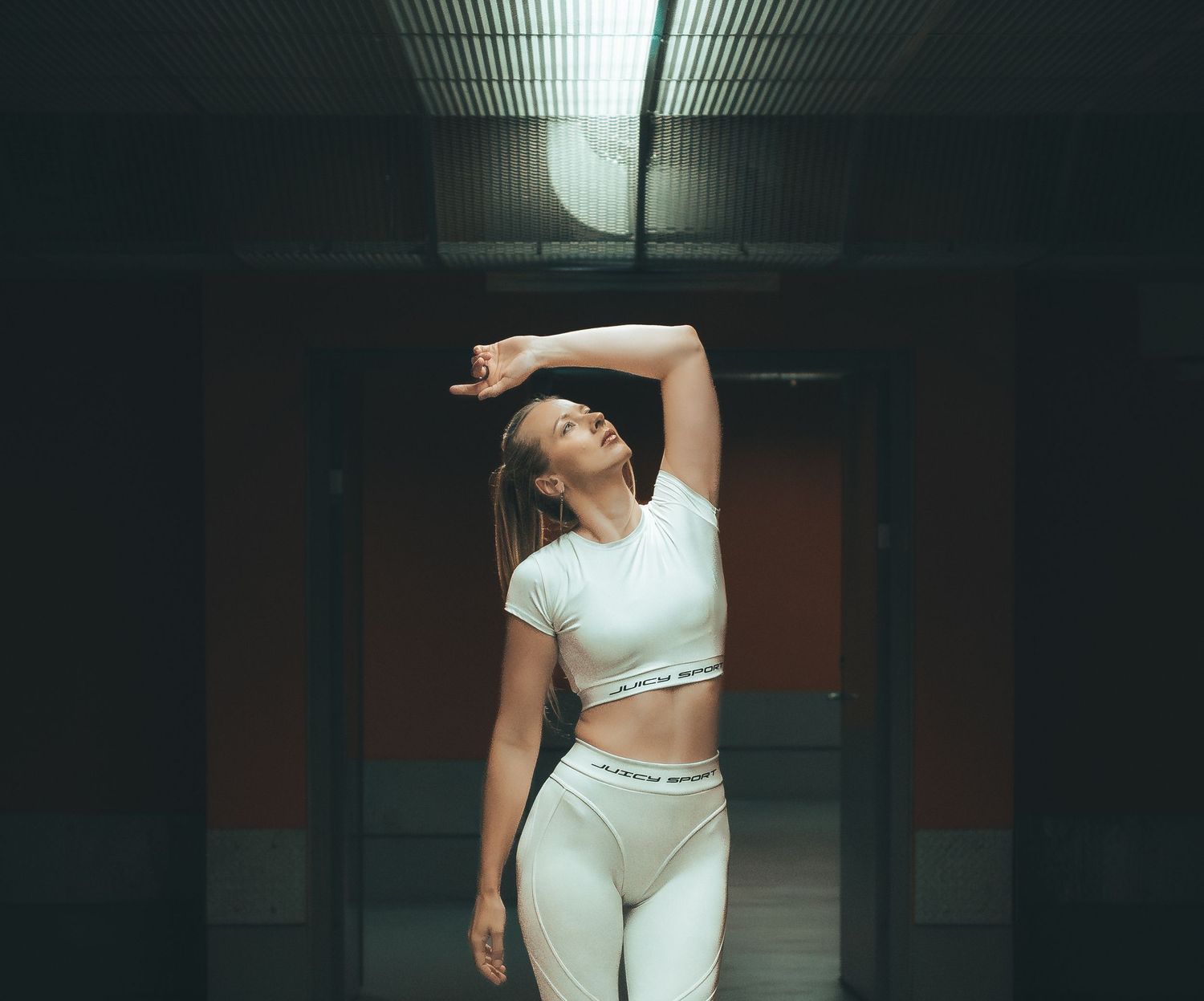 Photography of a female fitness model standing under soft light. Captured by Photopazo, a photographer in Malmö, Sweden.