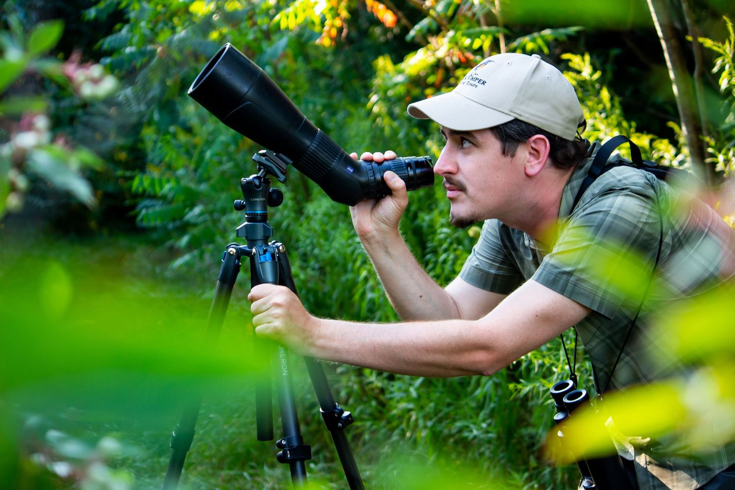 Toronto Portrait Photographer - Nature photographer using spotting scope on tripod amid green foliage.