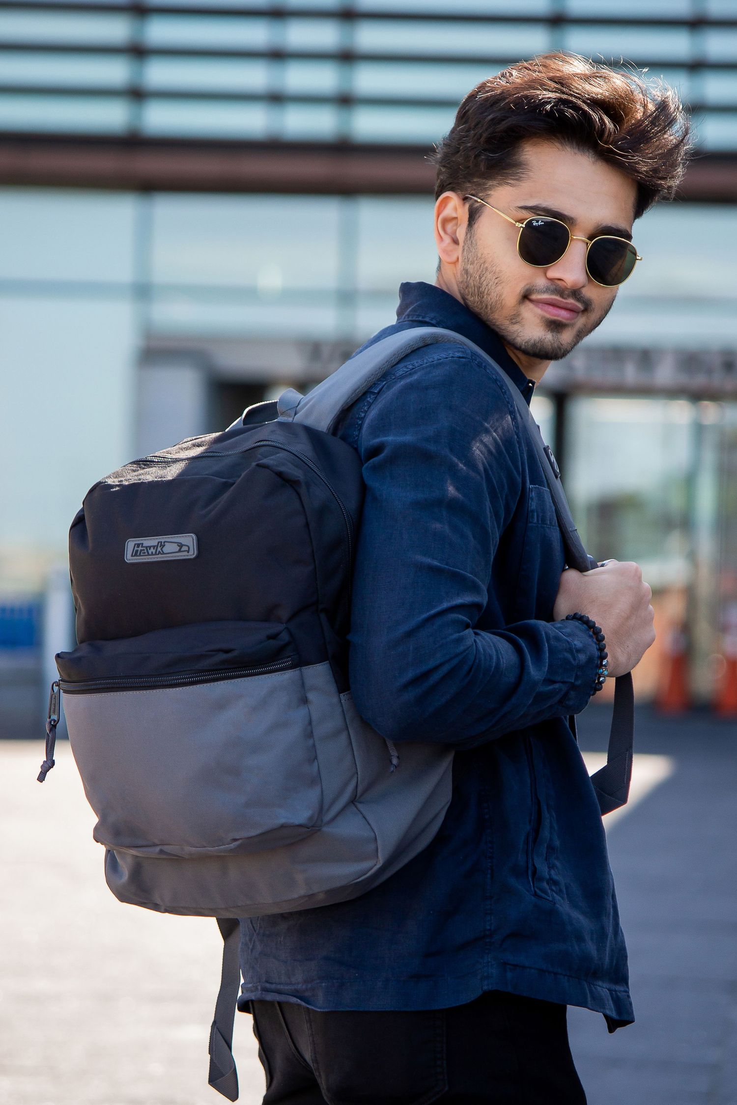 Toronto Portrait Photographer - Stylish person wearing sunglasses and navy jacket carrying a gray backpack in an urban setting.