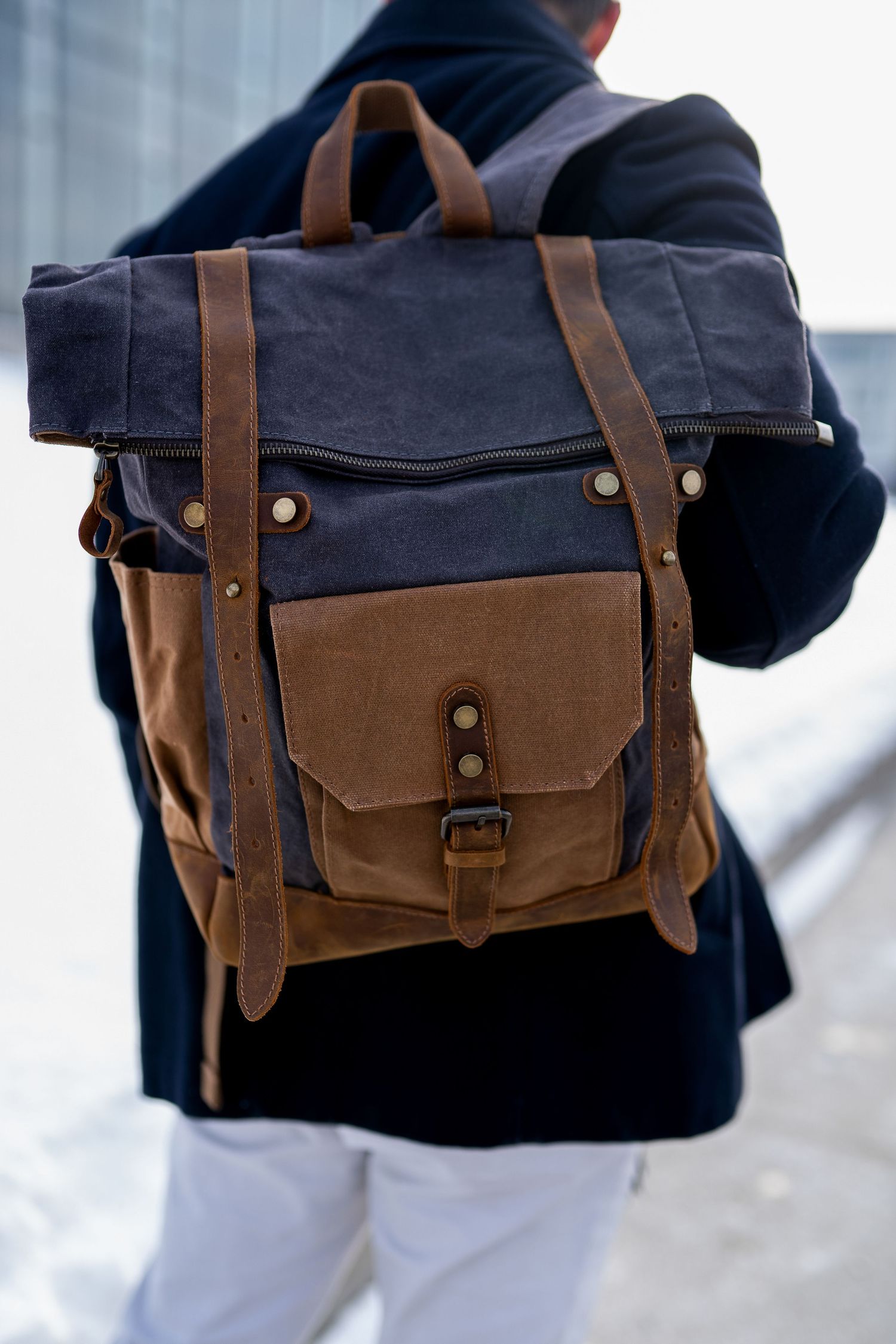 Toronto Product Photographer - Navy blue and brown canvas backpack with leather straps and brass hardware shown against light background.