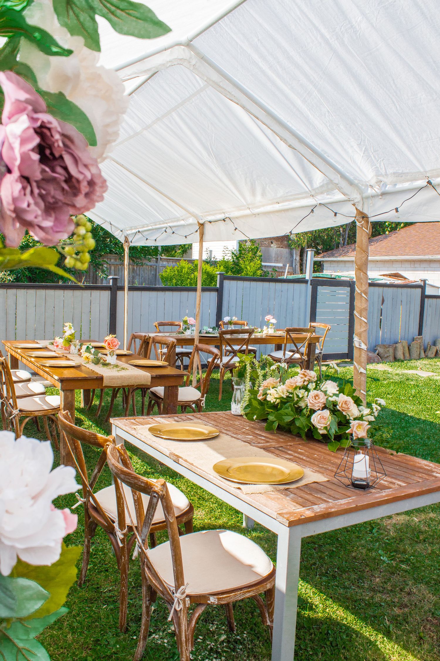 Toronto Event Photographer - Outdoor wedding reception setup under white tent with wooden tables and floral decorations.