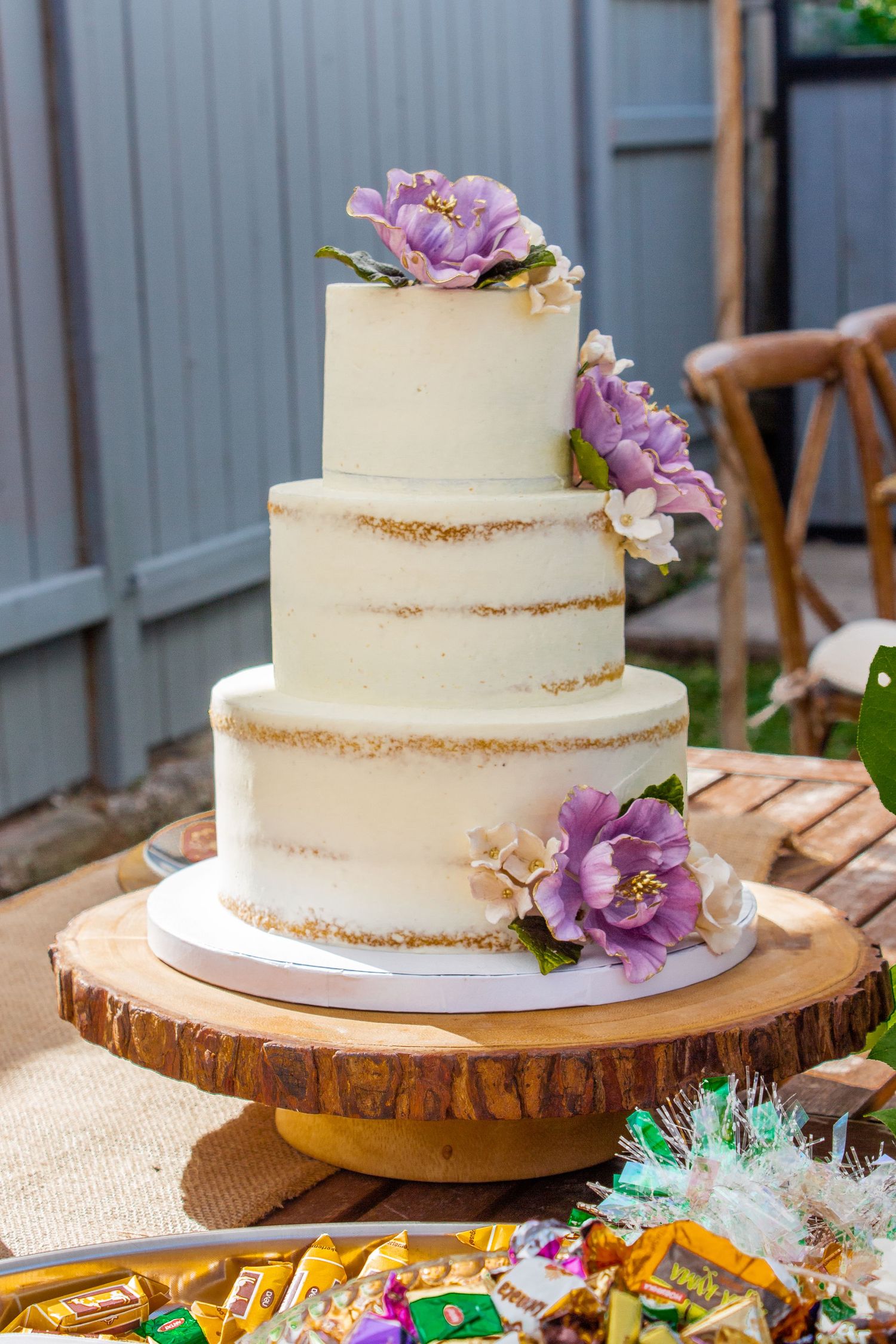 Toronto Event Photographer - Semi-naked white wedding cake decorated with purple flowers on wooden cake stand.