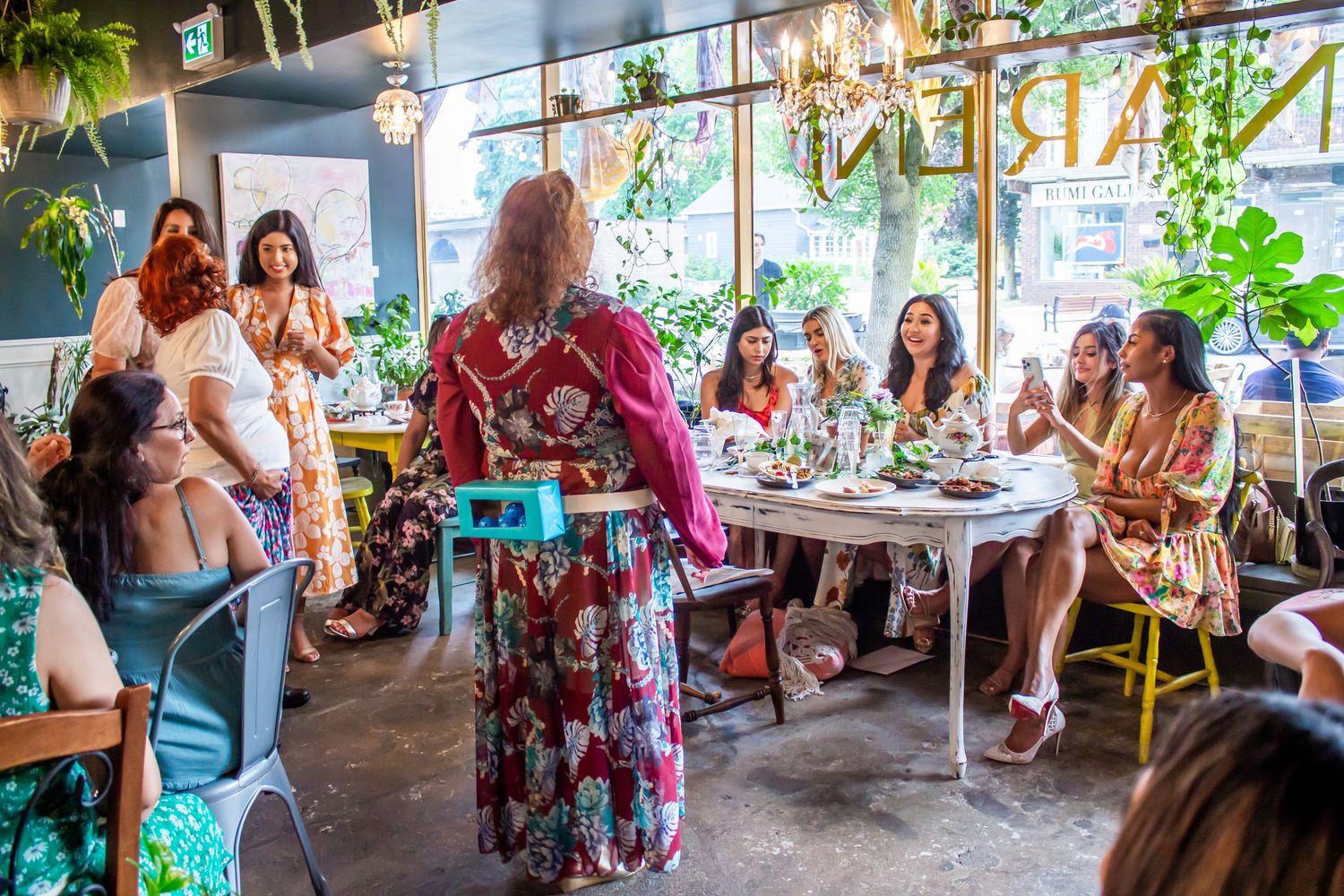 Toronto Event Photographer - A lively gathering at a botanical-themed cafe with chandeliers and natural lighting.