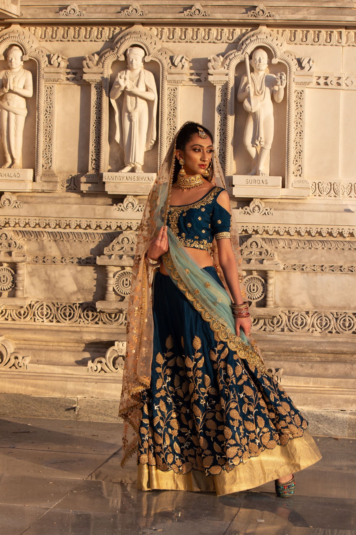 Toronto Portrait Photographer - Traditional Indian bridal attire featuring a navy and gold lehenga against ornate stone architecture.