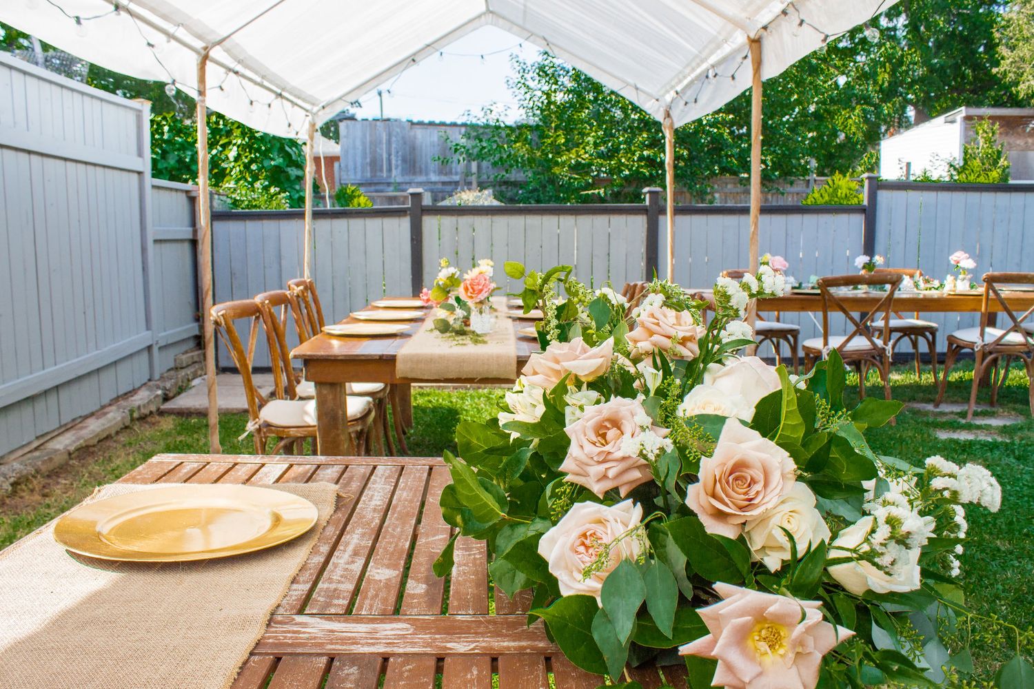 White tent setup with wooden tables and chairs for an outdoor event.