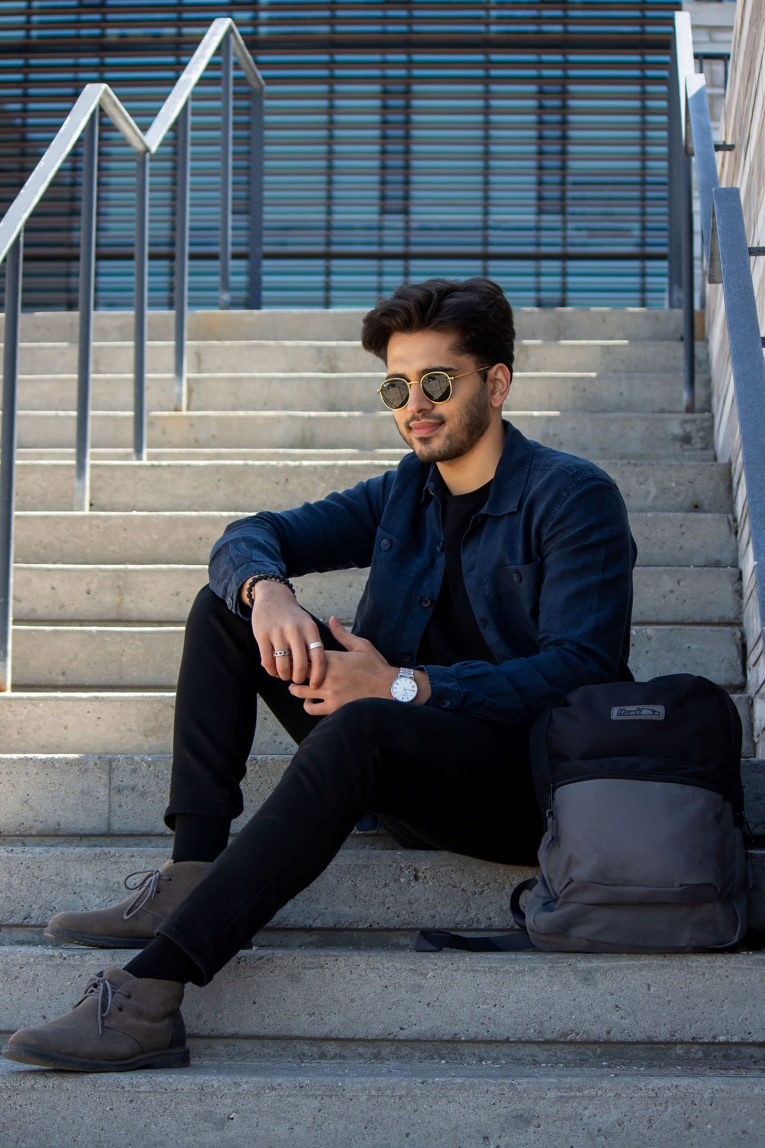 Toronto Portrait Photographer - Casual portrait on concrete steps with backpack and modern architecture in background.