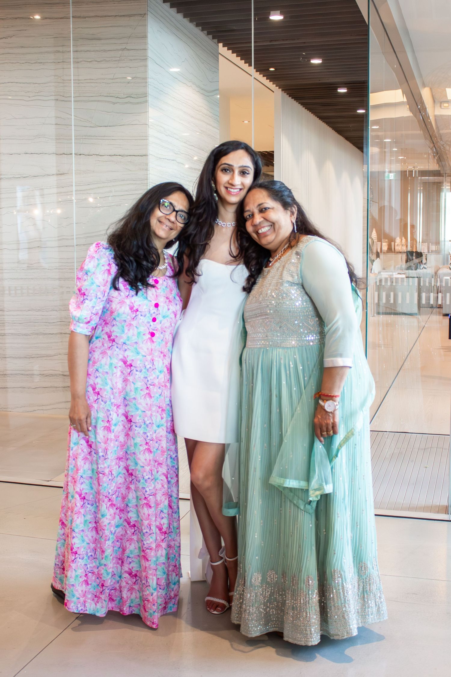 Toronto Event Photographer - Three women in festive attire posing together at an elegant indoor venue.