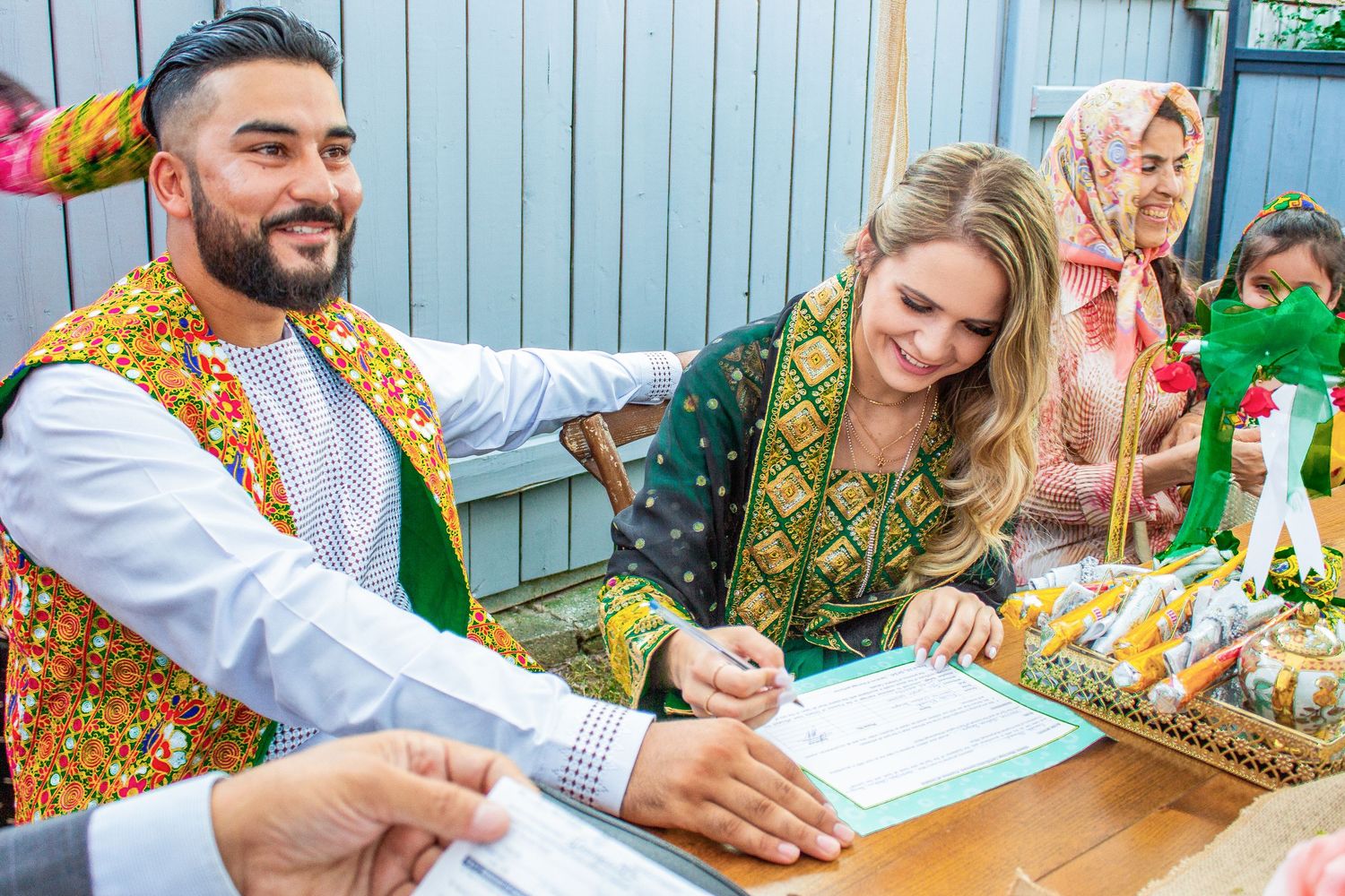Toronto Event Photographer - Couple in traditional South Asian wedding attire signing documents at an outdoor celebration.