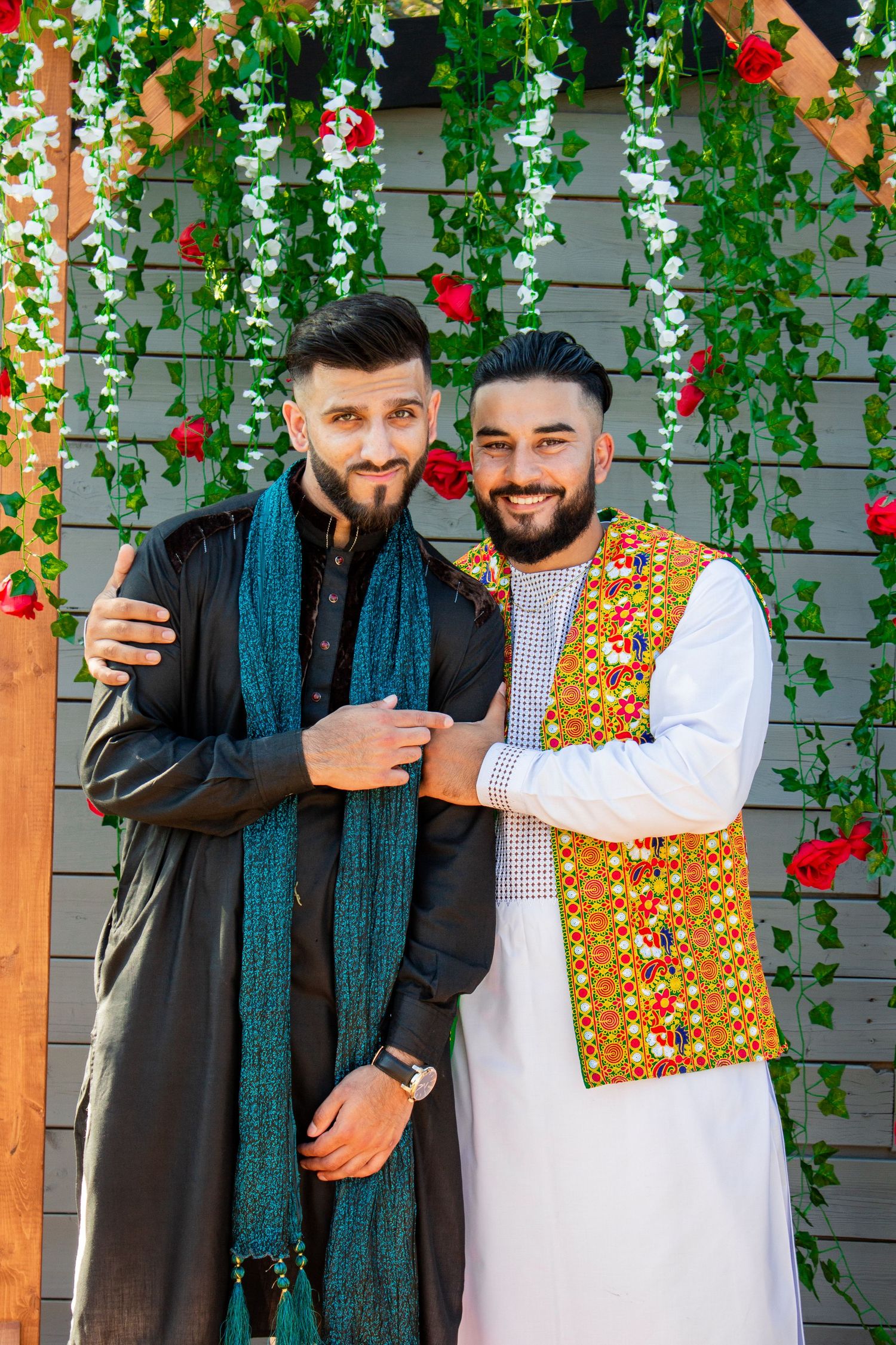Toronto Event Photographer - Two friends in traditional South Asian formal wear posing against floral wall decoration.