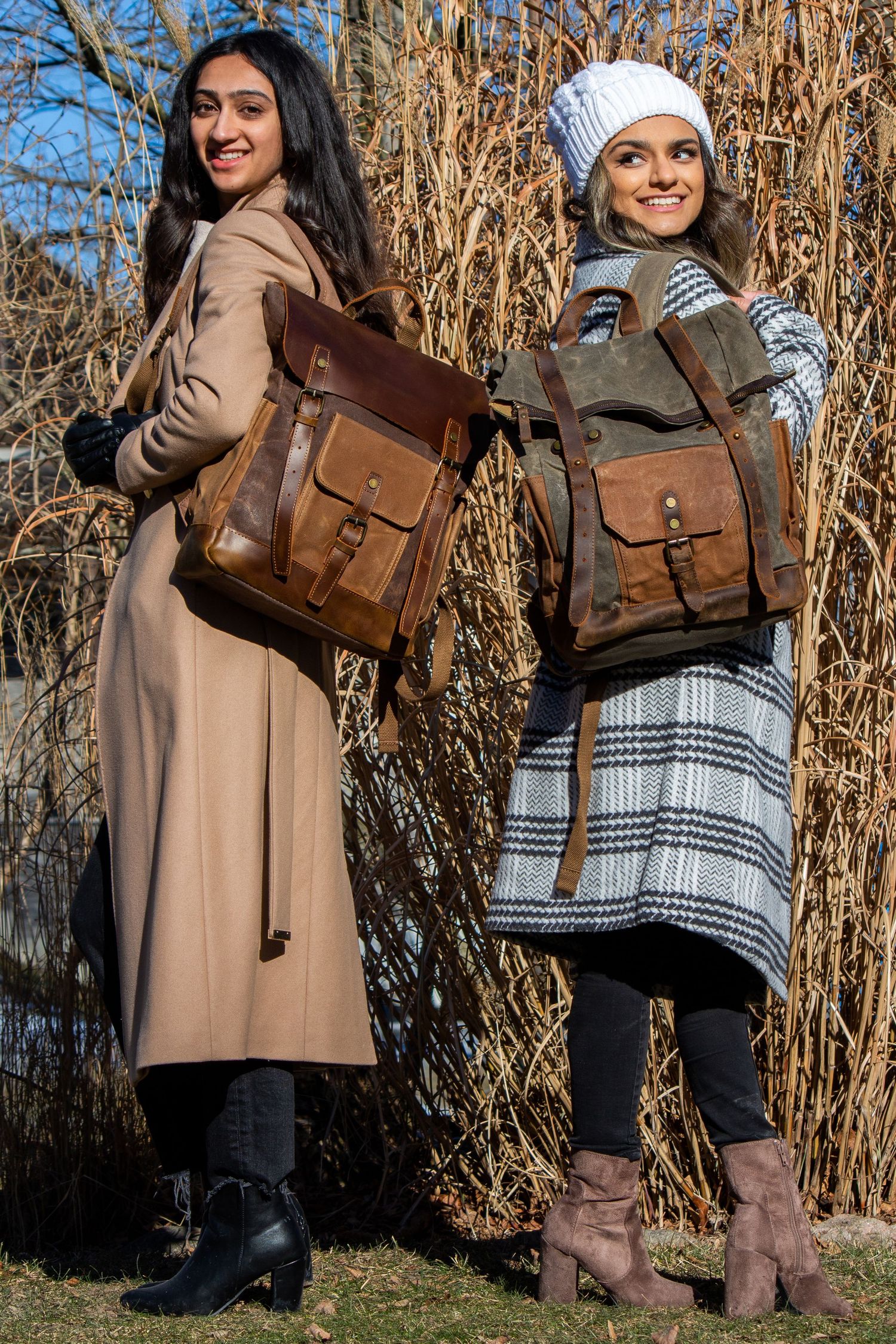 Toronto Portrait Photographer - Two models showcase brown leather backpacks wearing winter coats against dried reeds.