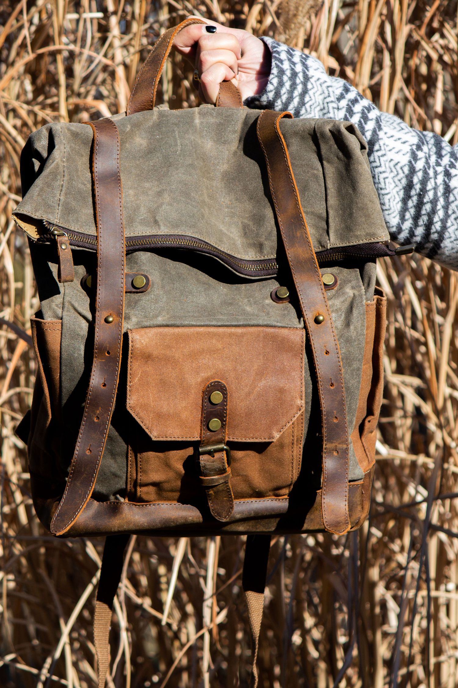 Toronto Product Photographer - Vintage-style canvas and leather backpack with multiple pockets displayed against dried reeds background.