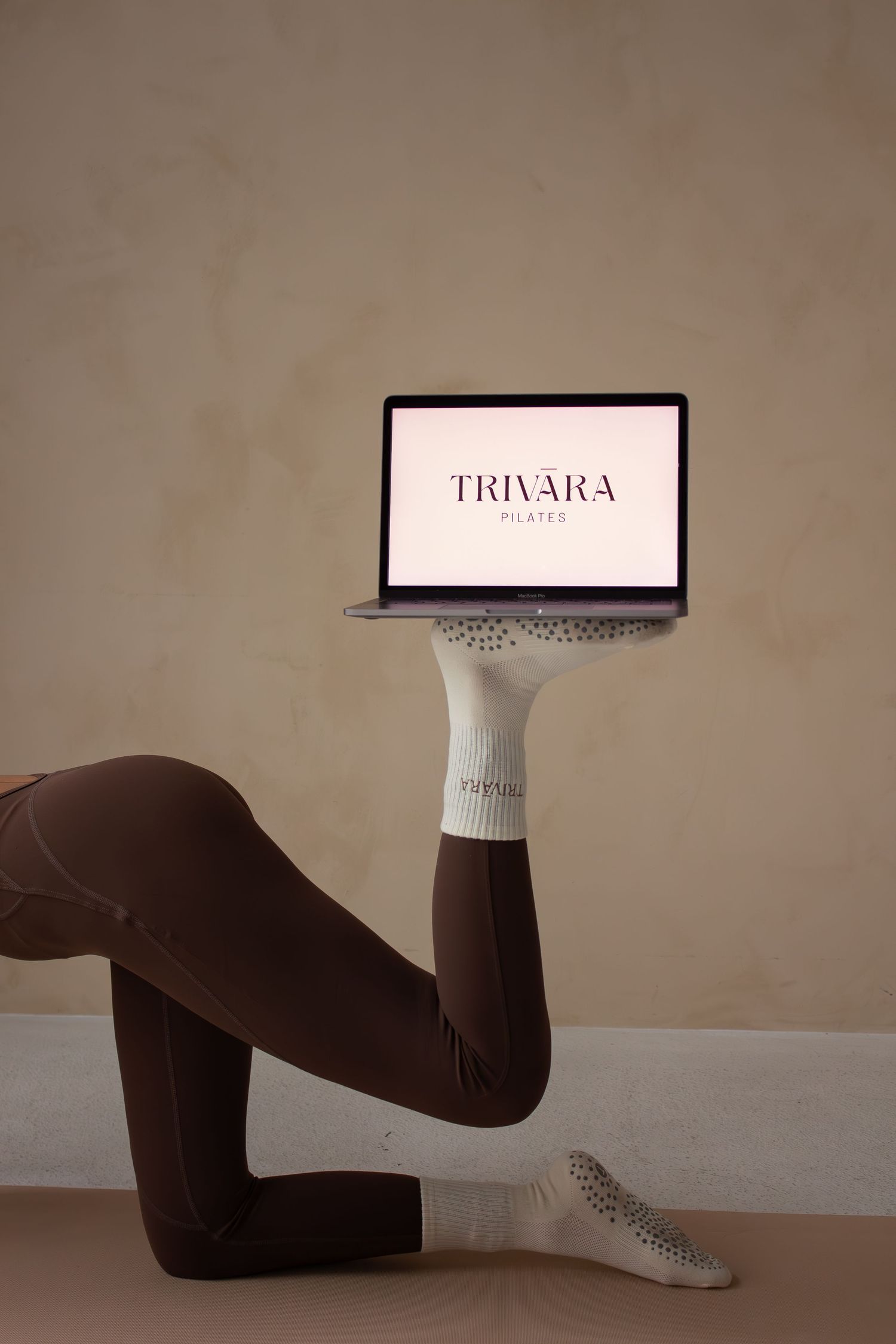 A minimalist photo sequence shows feet in white socks performing pilates exercises against a neutral beige wall.