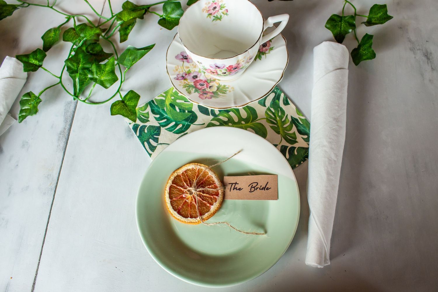 Toronto Event Photographer - Vintage teacup setting with dried orange slice and green ivy on white marble surface.