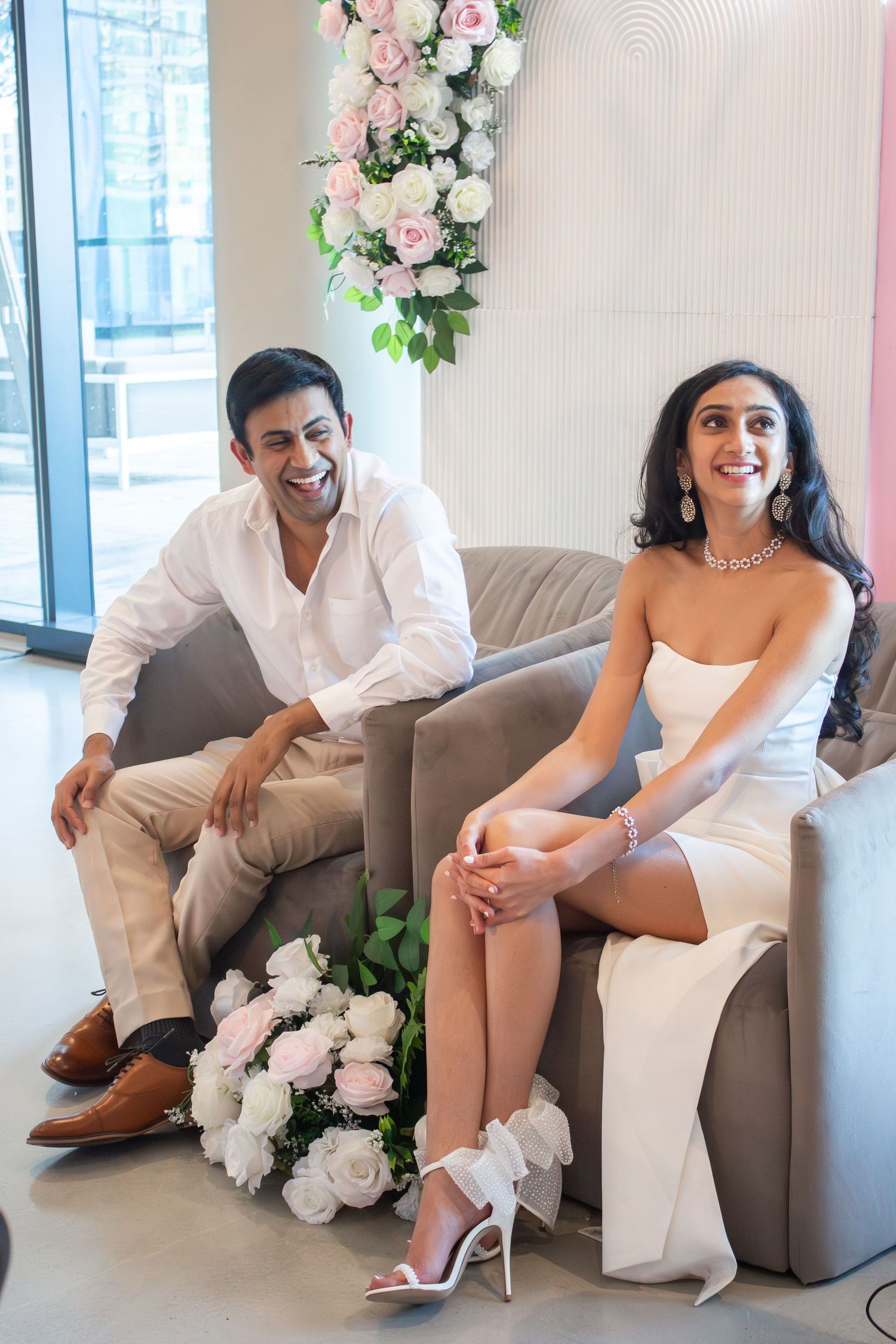 Toronto Event Photographer - Couple relaxing on grey sofa with floral decorations in modern interior setting.