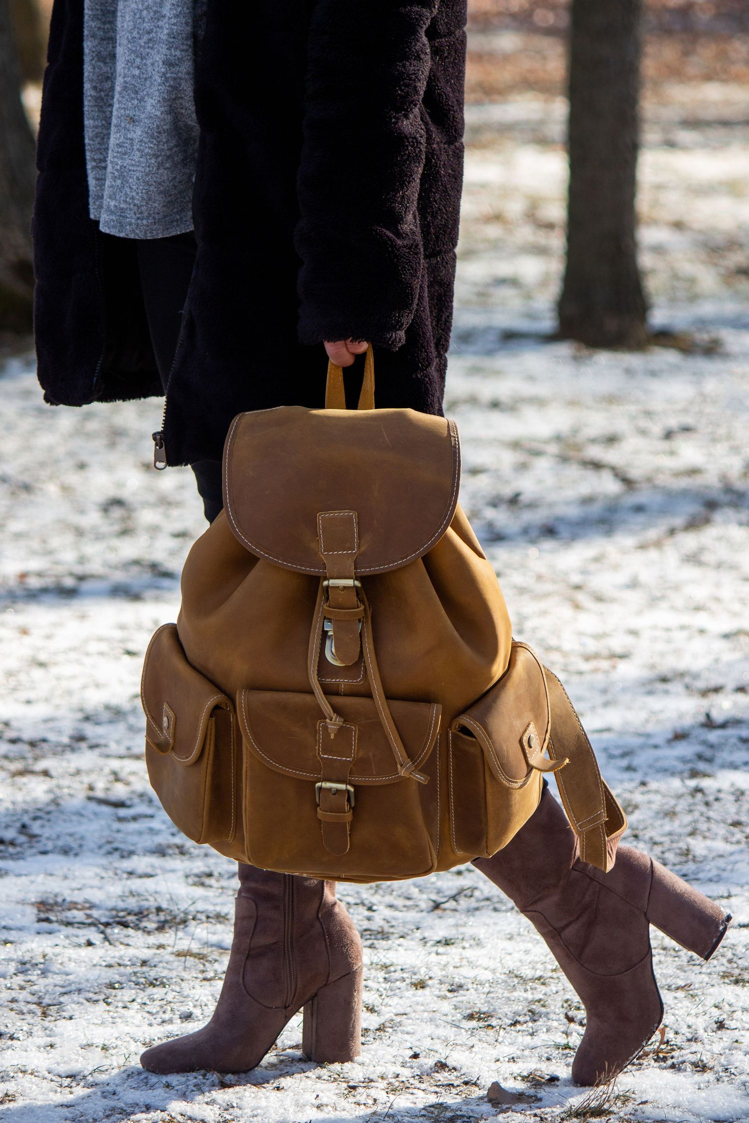 Toronto Product Photographer - Brown leather messenger bag and brown boots shown against snowy ground.