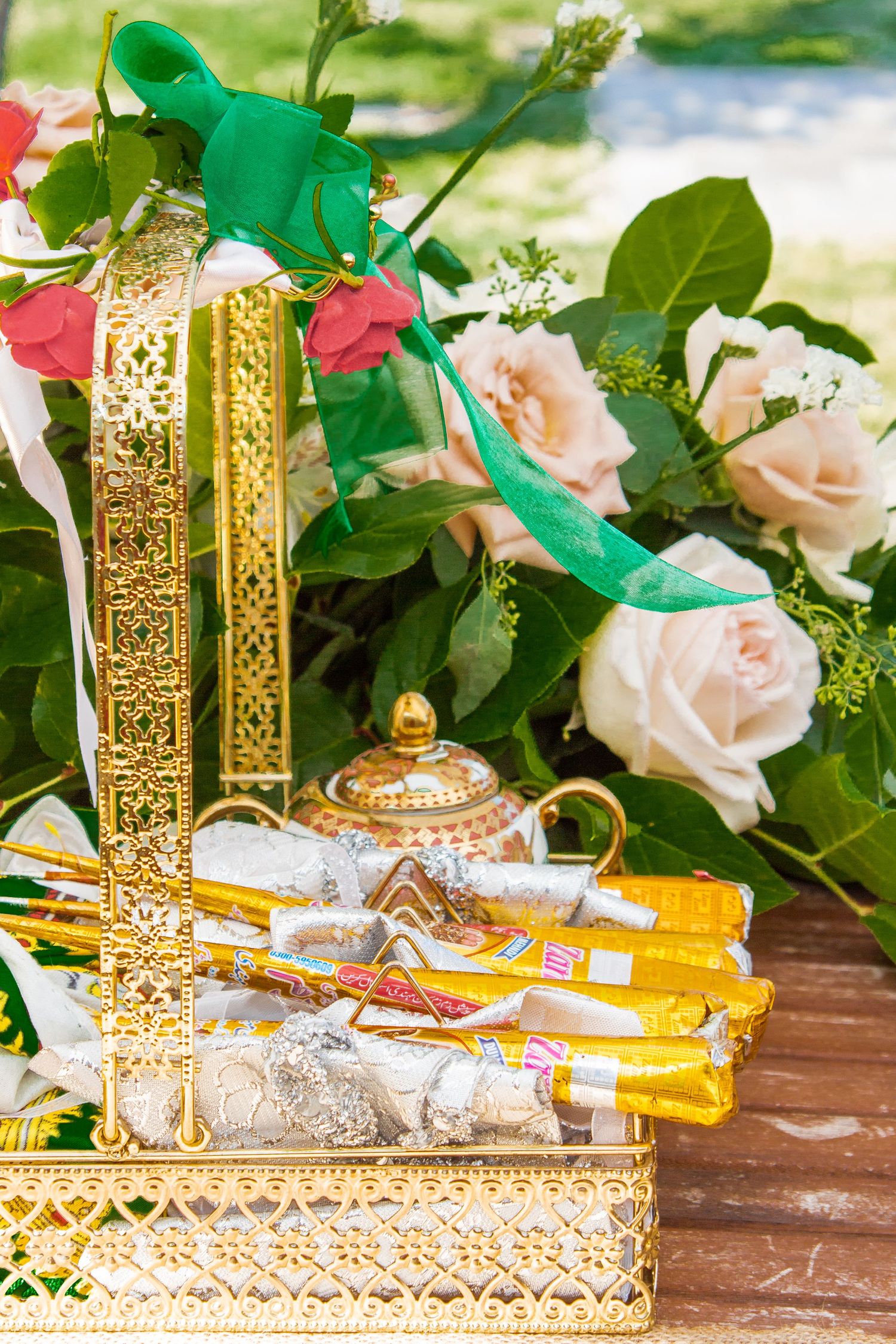 Toronto Event Photographer - Ornate gold decorative pieces arranged with pink roses and greenery on wooden surface.