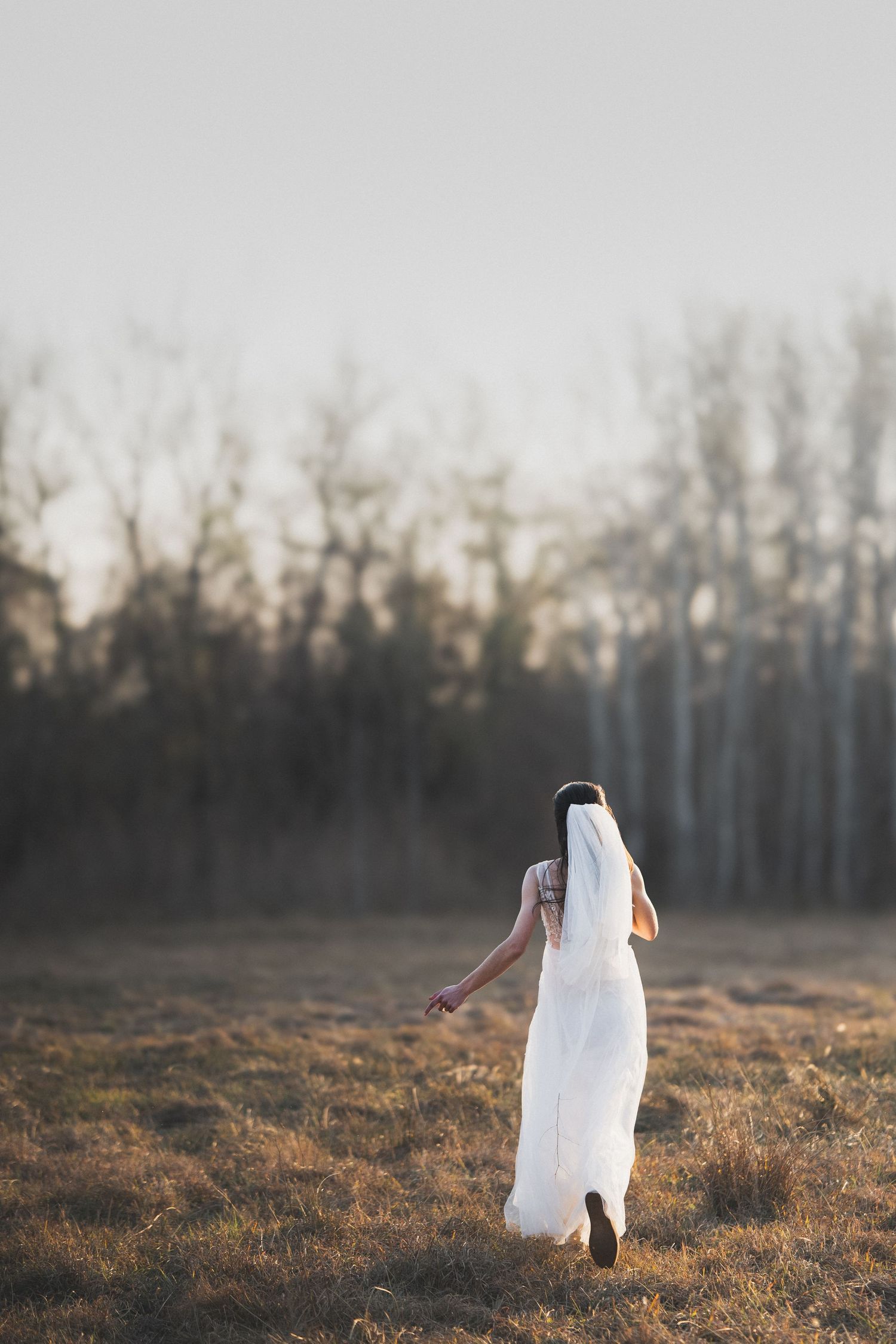 Bride running through an open field during a wedding portrait