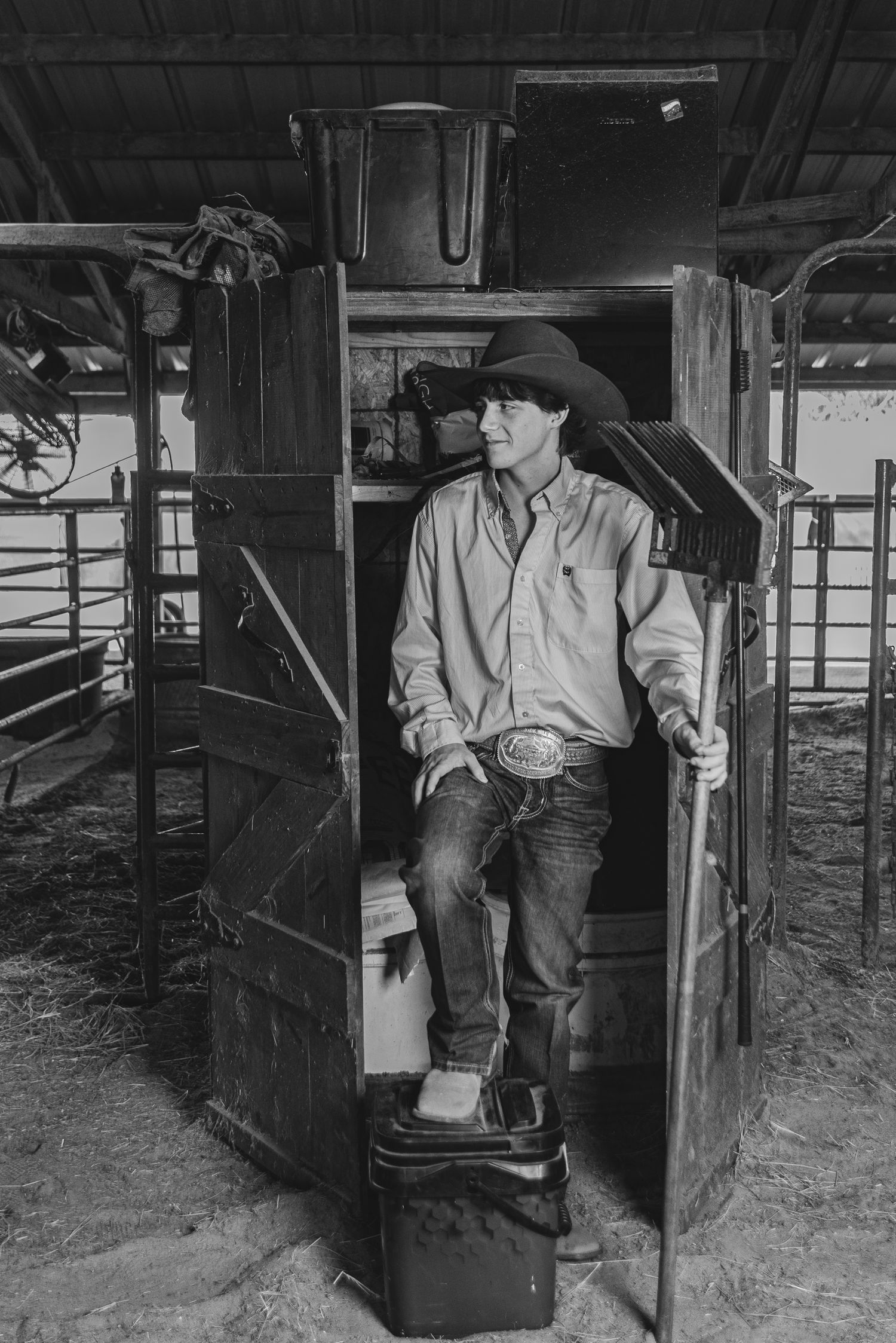 A western-styled figure stands in a wooden stable doorway wearing traditional ranch attire.