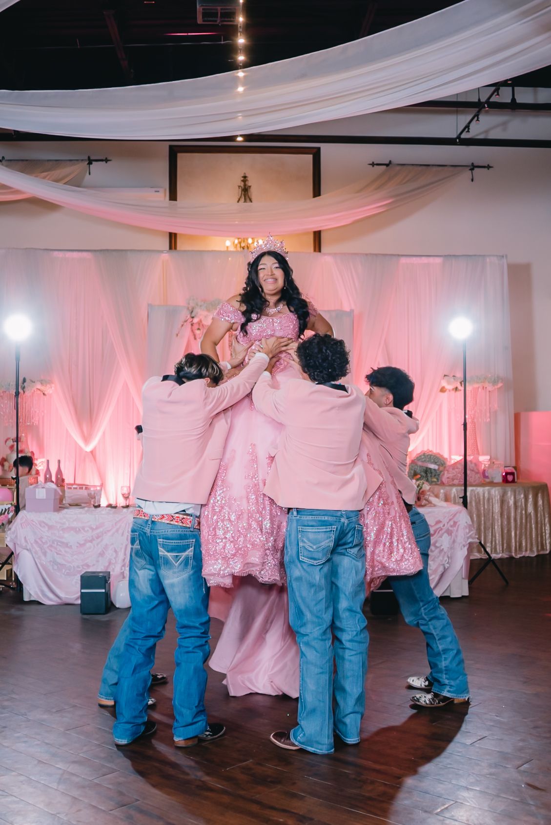 Choreographed dance performance in a ballroom with pink lighting and white decor.