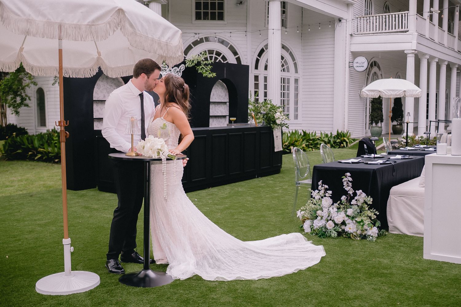 Outdoor wedding venue with classic white colonial architecture and manicured lawn.