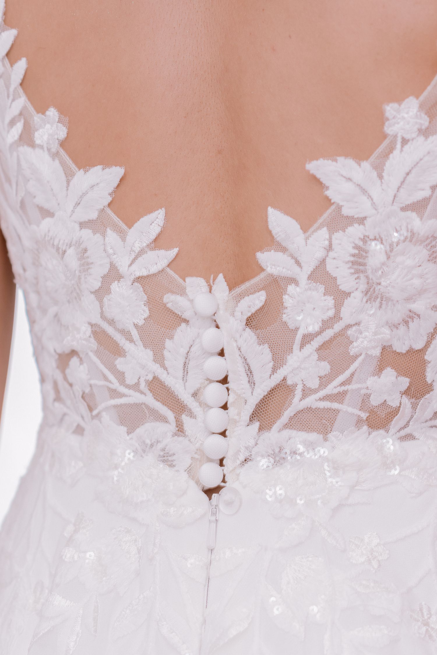 Delicate white lace floral applique detail on sheer fabric.