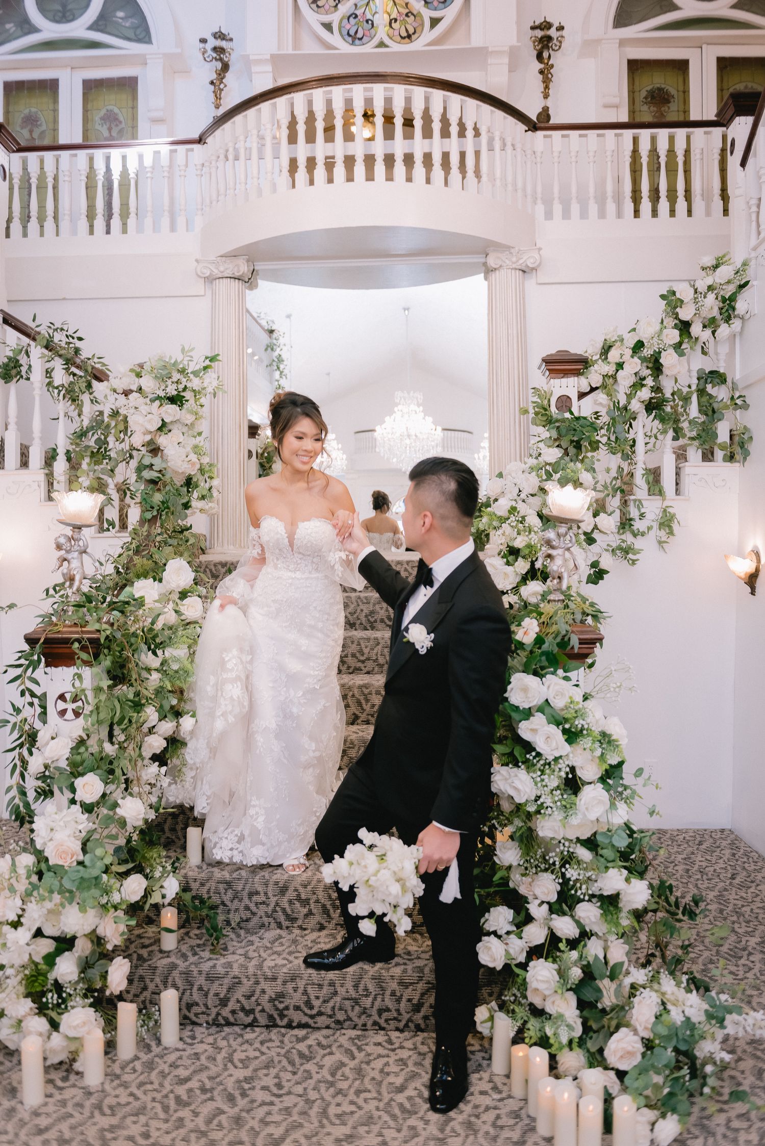 Romantic wedding ceremony setup with white floral arch and candle-lined aisle in elegant venue.