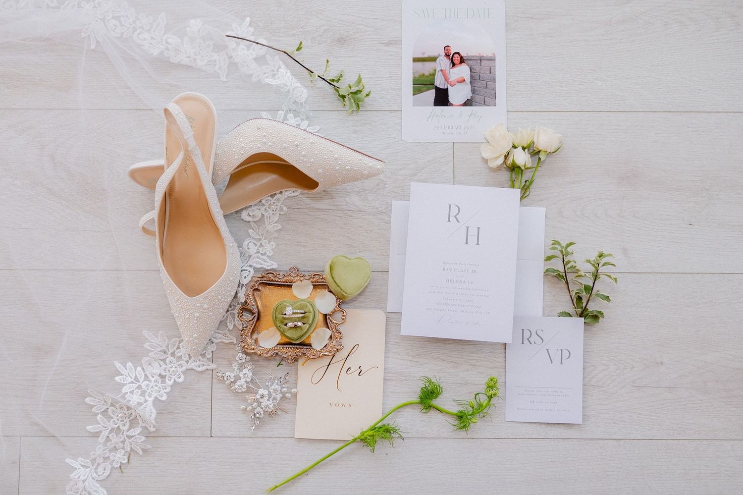 Wedding invitation suite with nude heels and delicate floral accents on white wooden background.