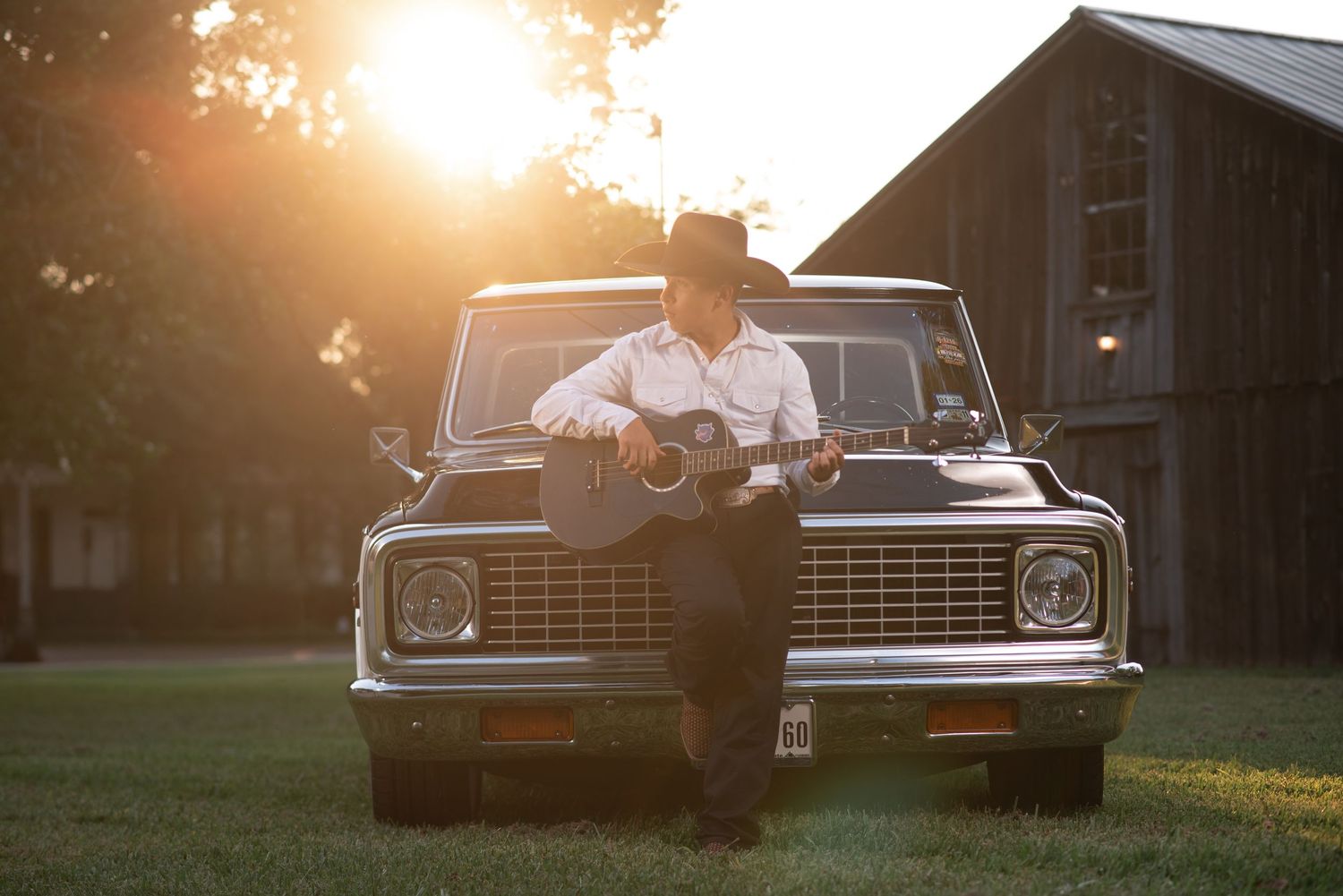 Golden hour portrait session with vintage car and barn in background.