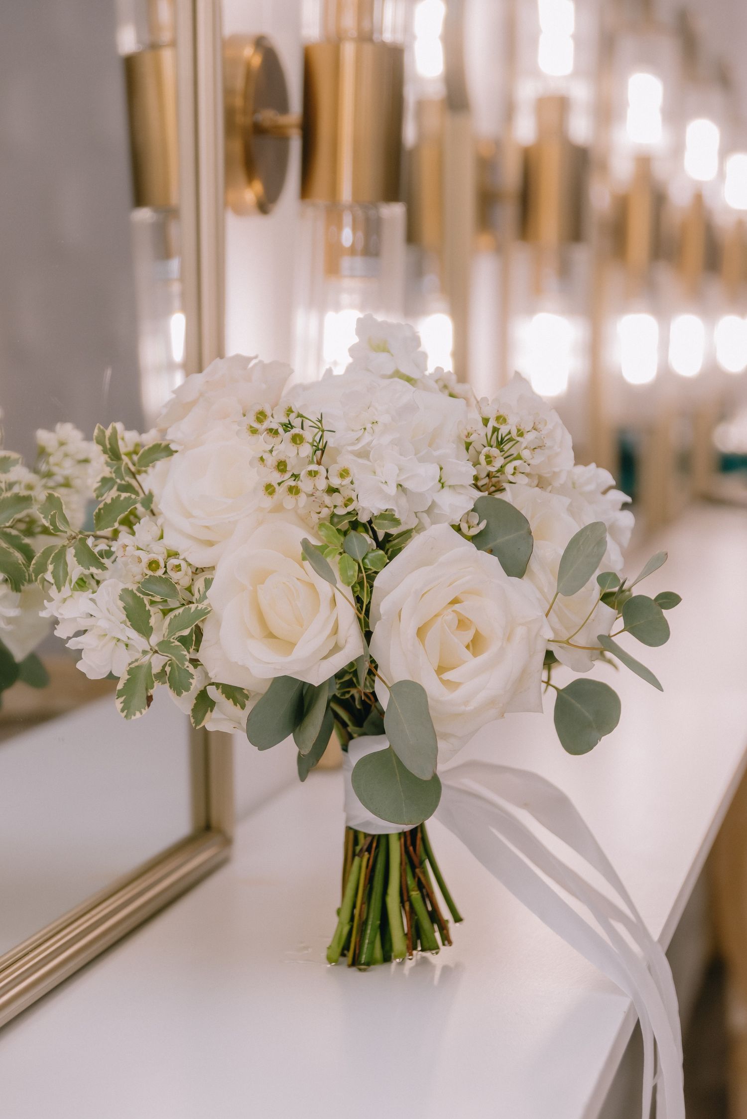 Elegant white rose and eucalyptus wedding bouquets arranged in a row with soft lighting.