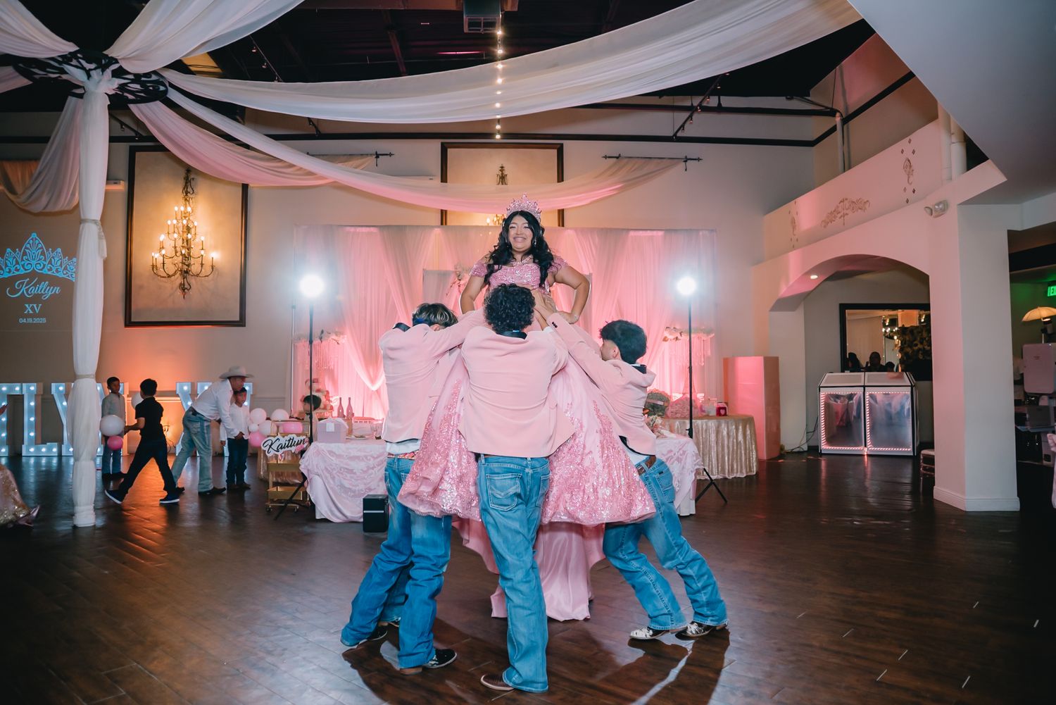 Festive dance sequence in a pink-lit ballroom with white draping.