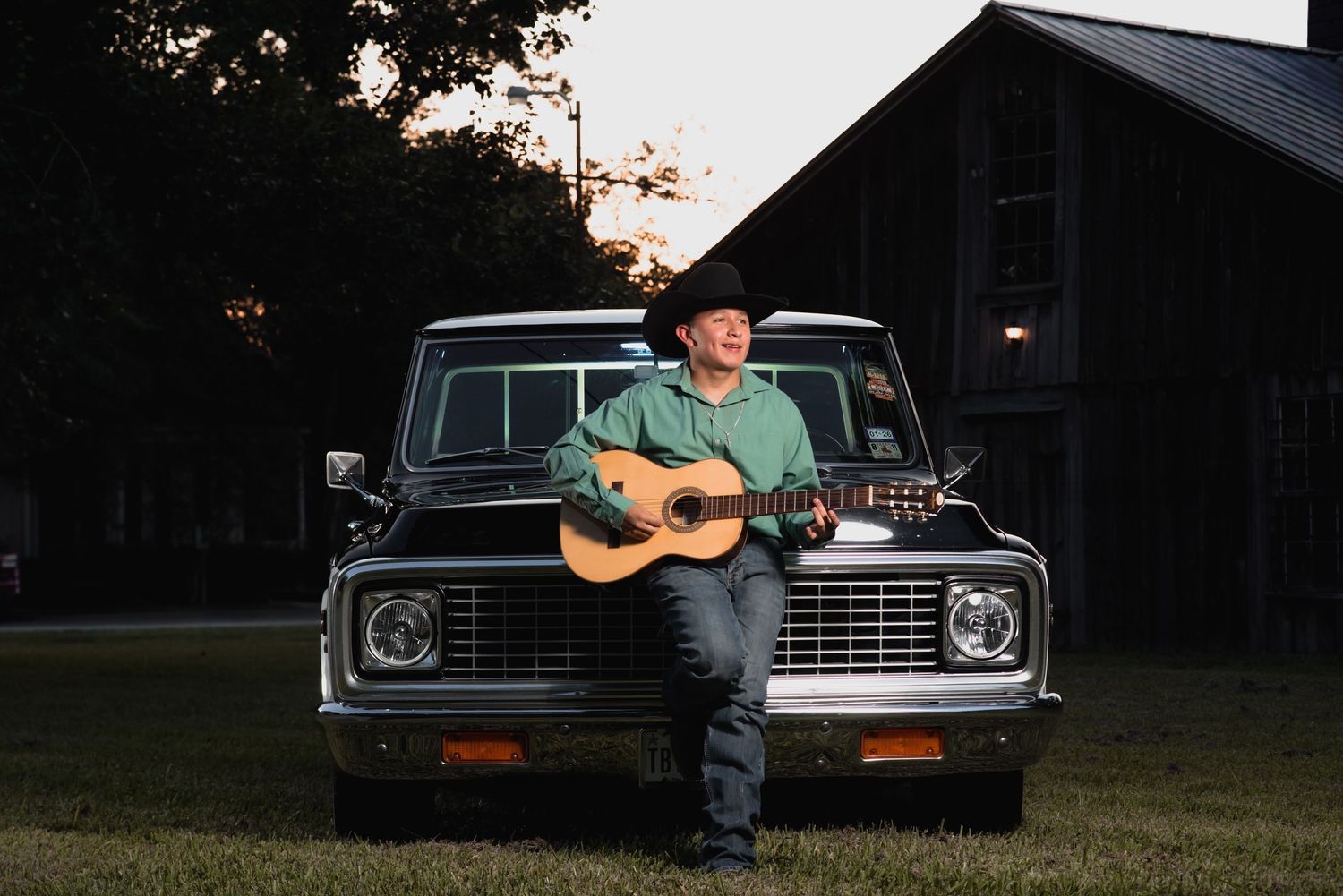 Sunset photoshoot with classic car and guitar player in rural setting.