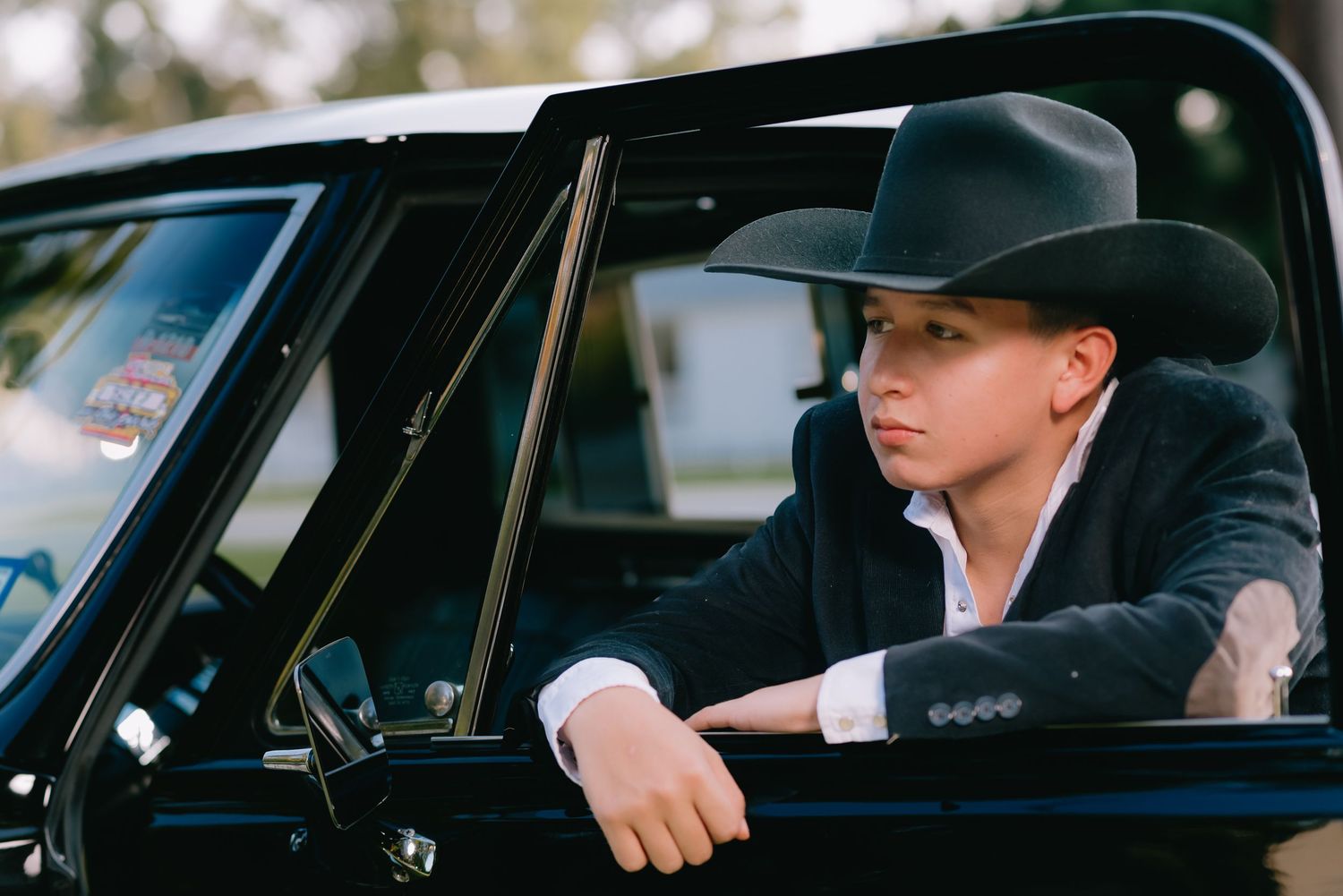 Person in black cowboy hat sitting in vintage car interior.