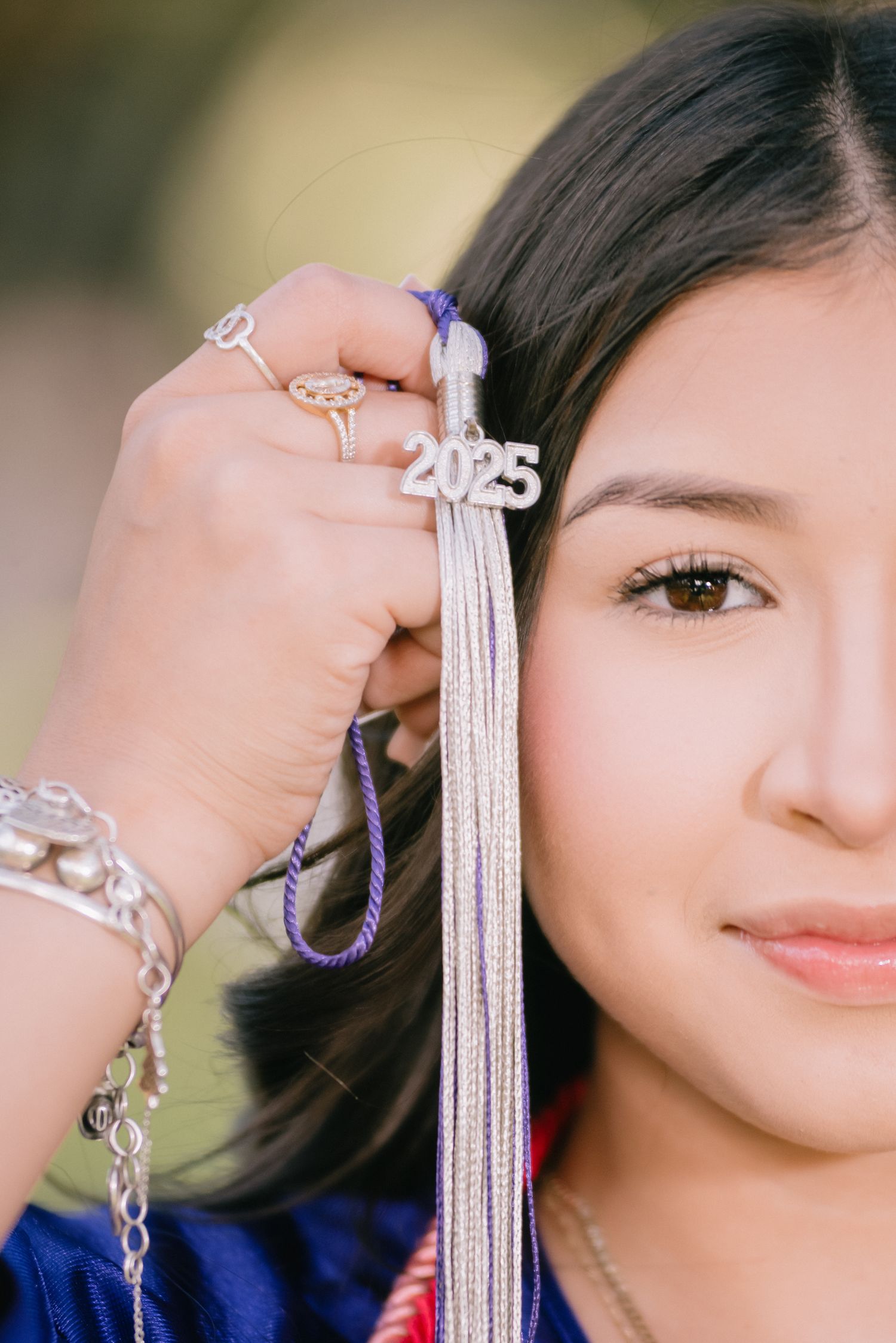 Close-up shot showing graduation tassel and jewelry with 2023 charm.