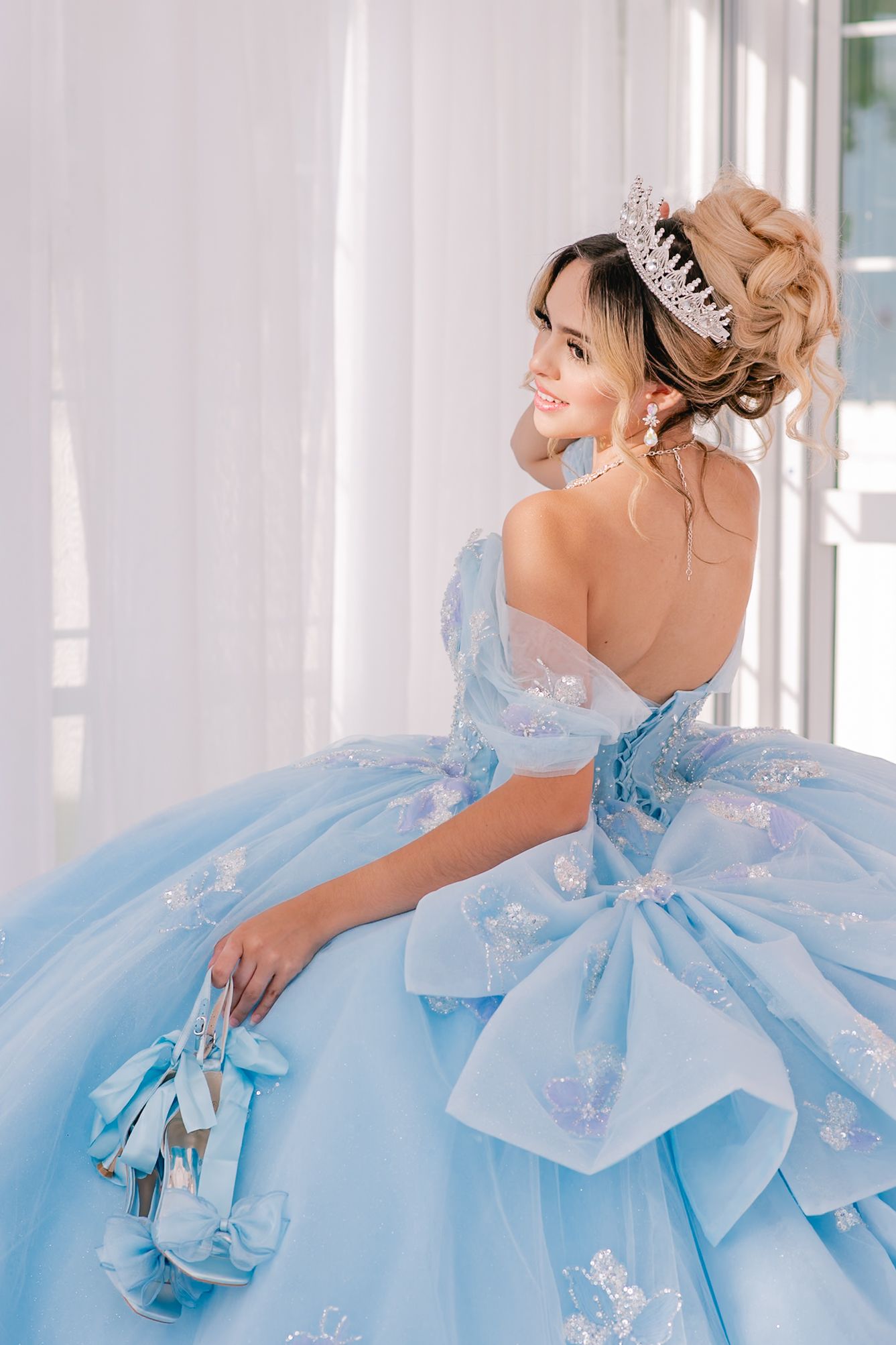 Close-up details of a powder blue ball gown featuring intricate bow designs and crystal embellishments.