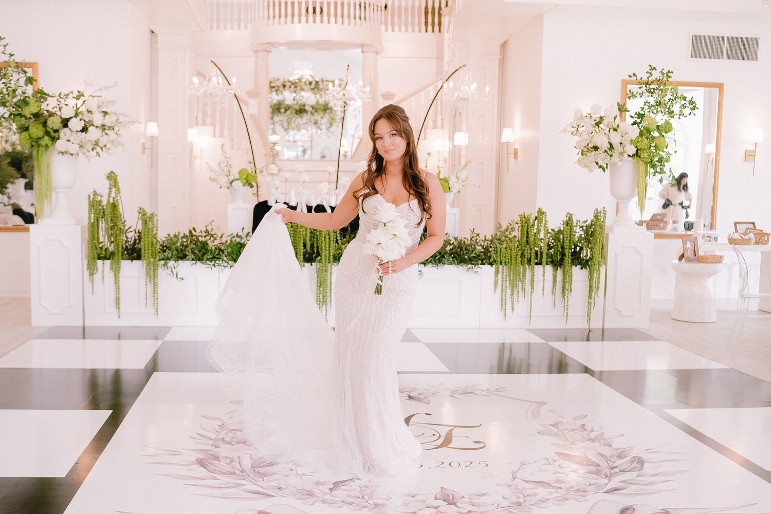 Modern white wedding venue interior with hanging greenery and minimalist decor.