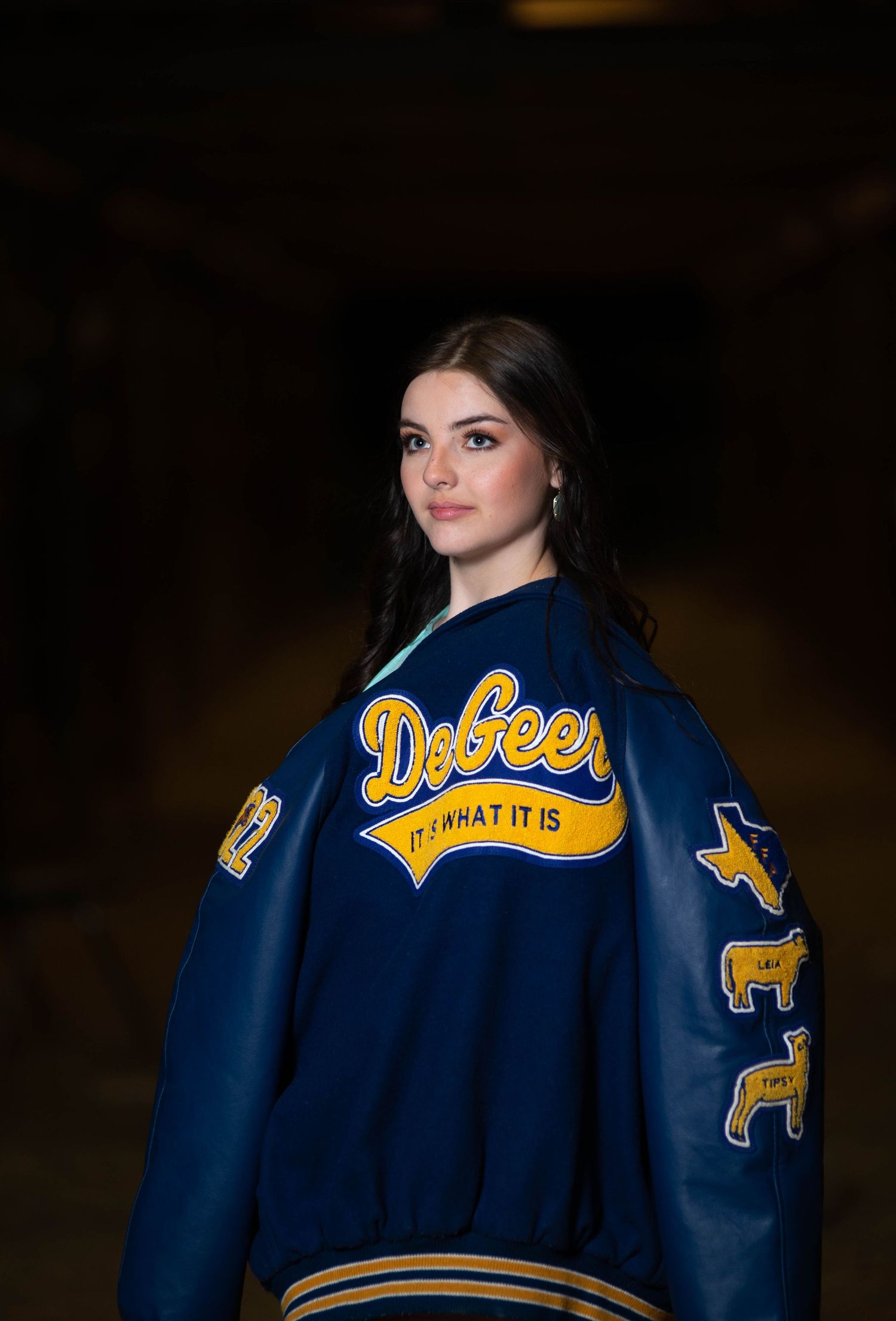 A letterman jacket with Defoe branding and animal patches photographed against a dark background.