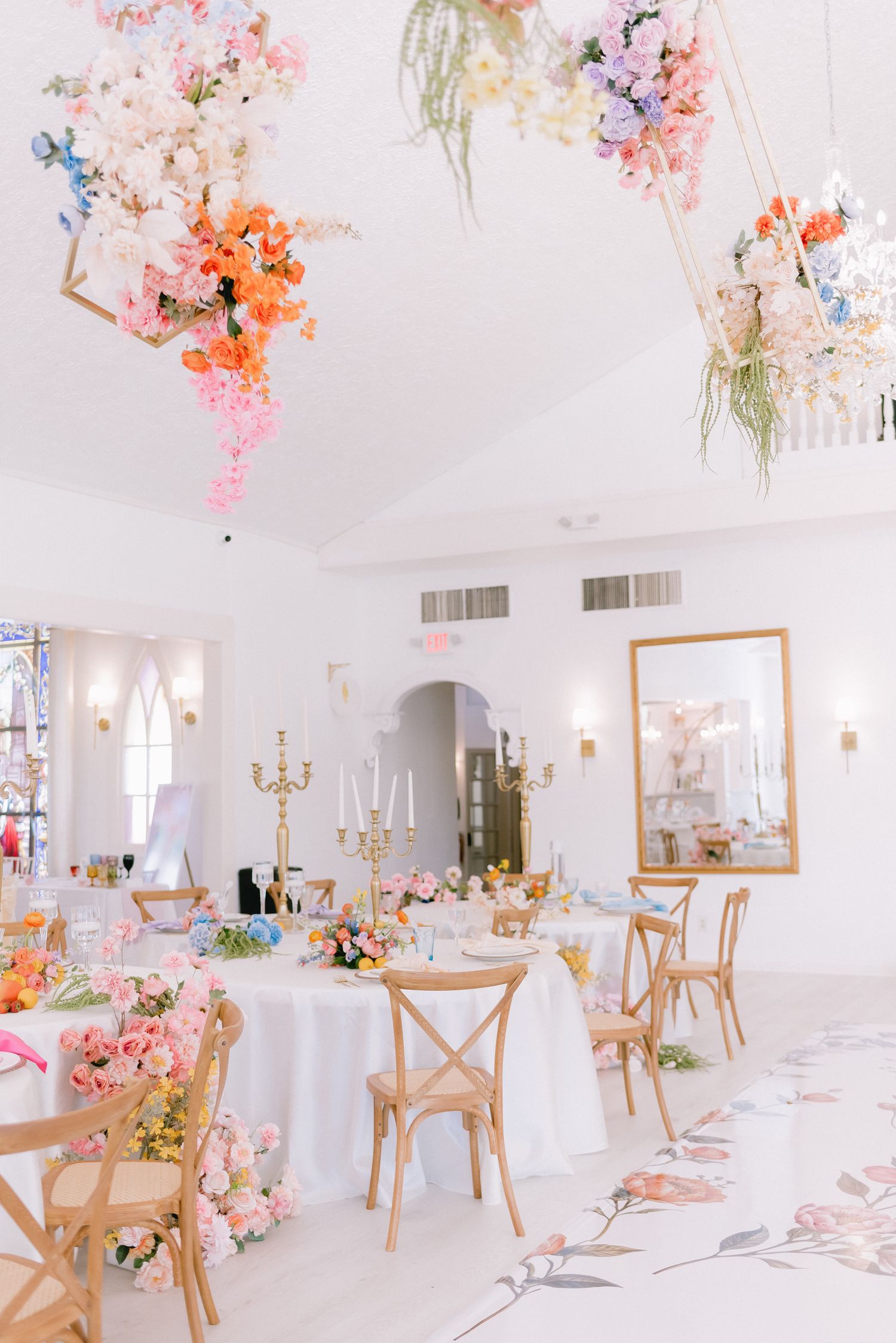 Elegant wedding reception venue with hanging floral arrangements and white table settings.