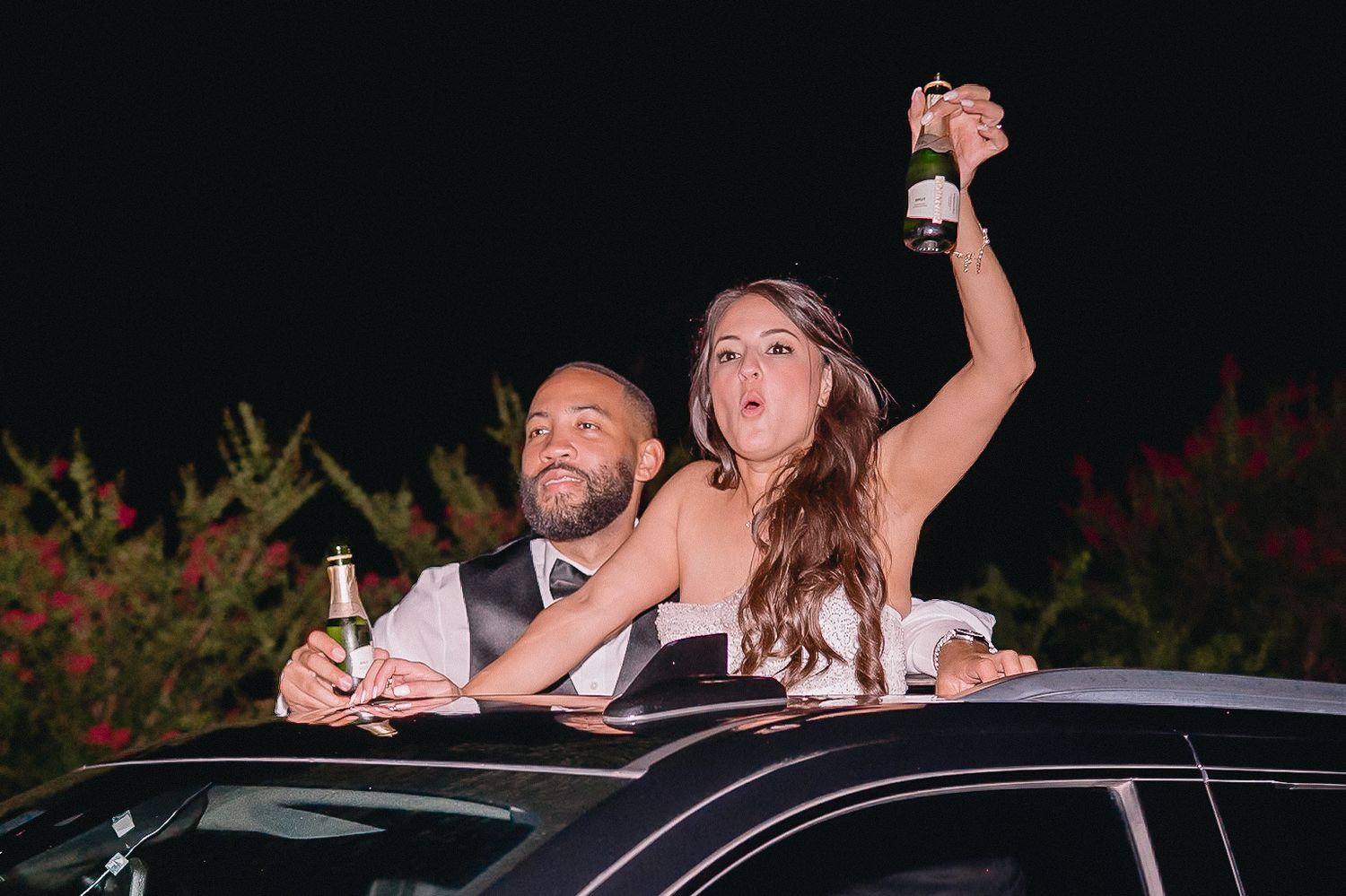 Wedding celebration at night with guests cheering from cars during a drive-by reception.